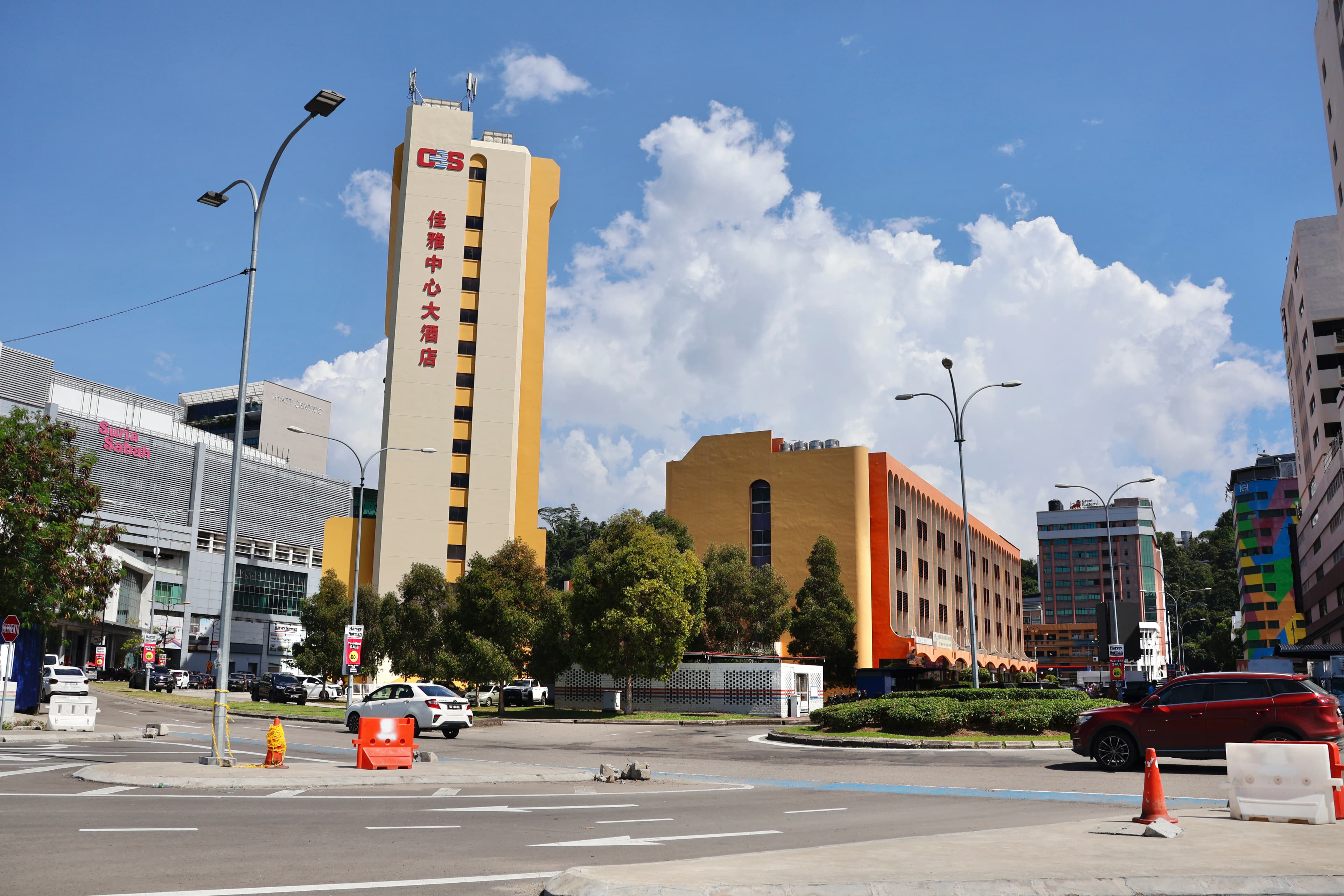 Tall buildings and trees under a cloudy sky.
