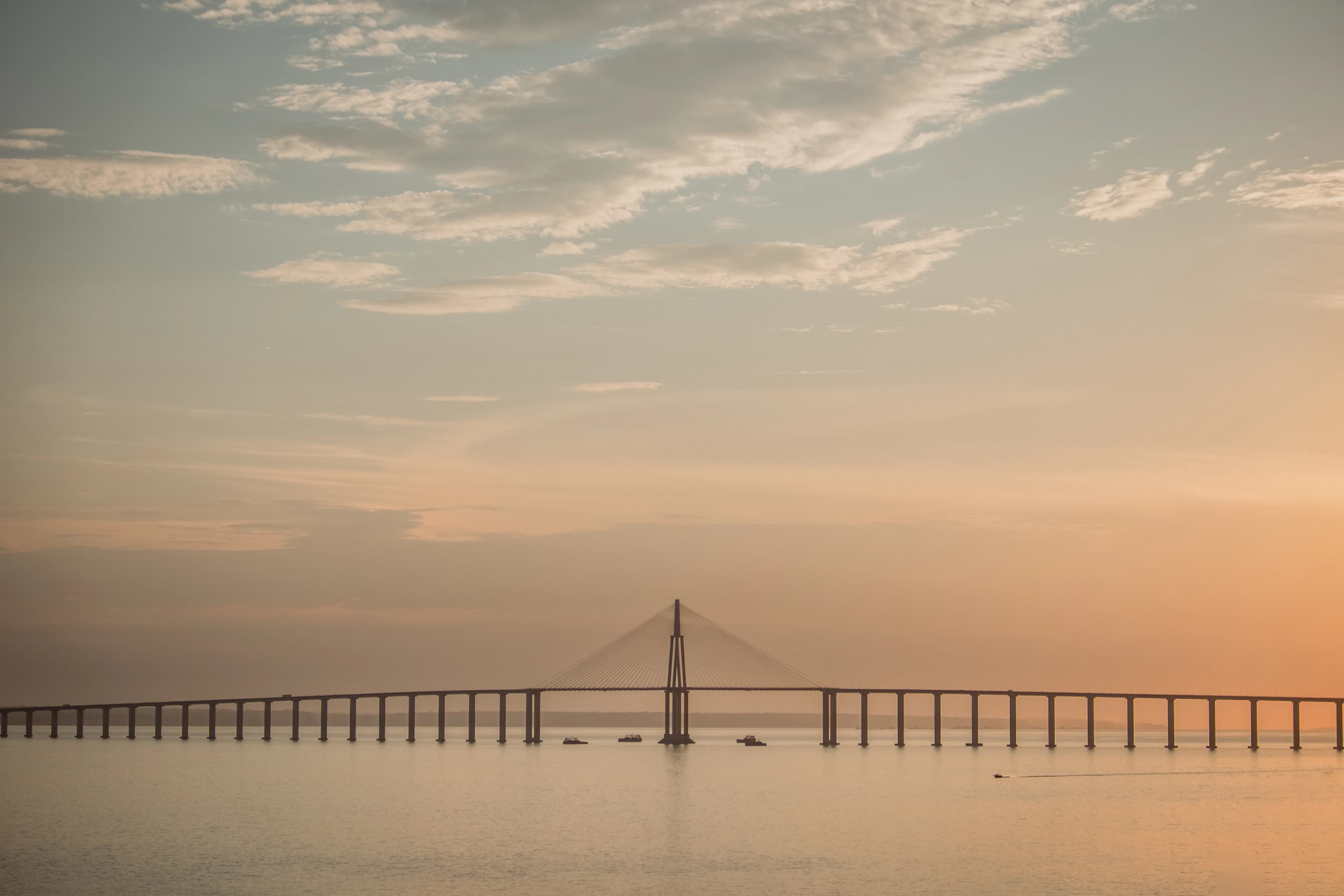 A long bridge spans across calm water.