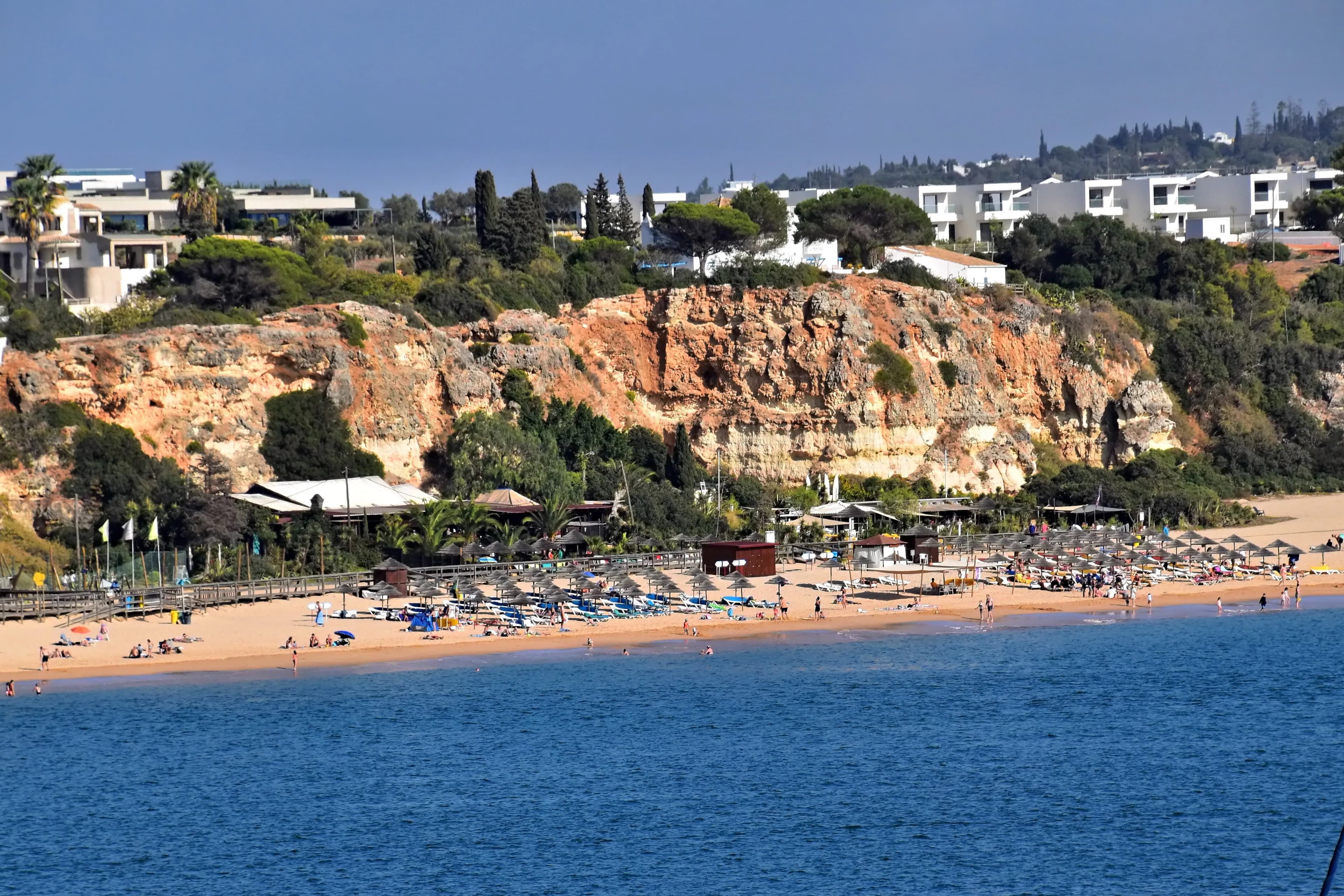 Beach with umbrellas and buildings on cliff above cliffside cliff