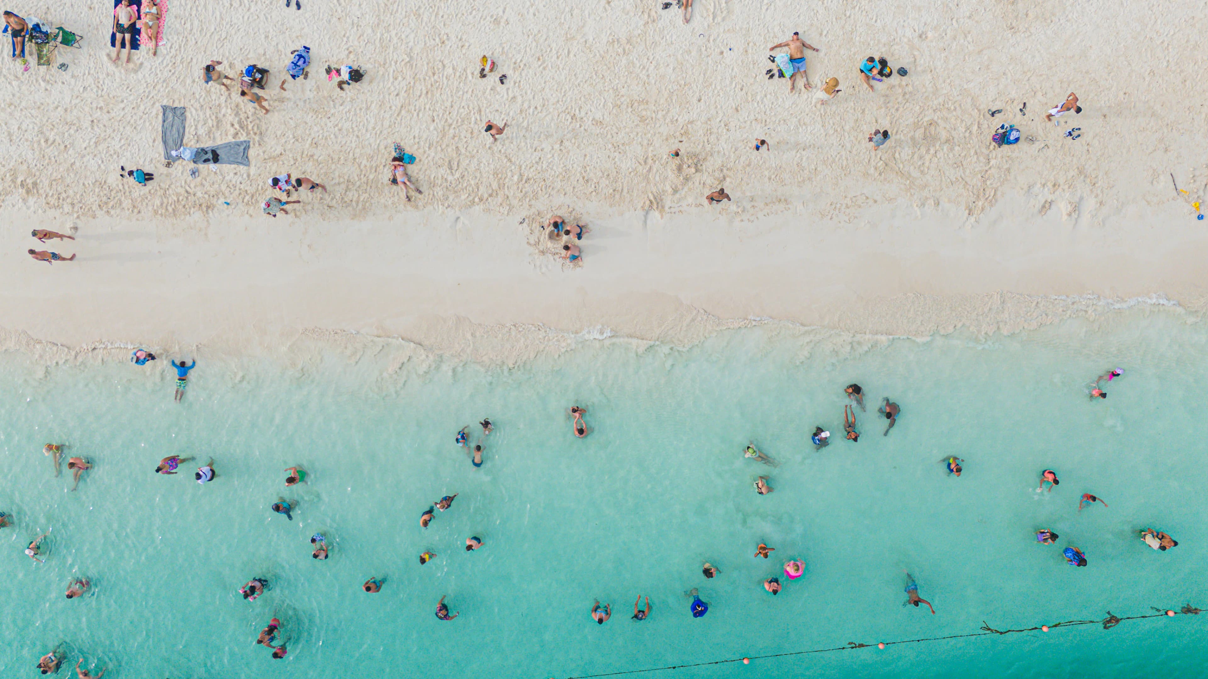People swim in the ocean and relax on the beach.
