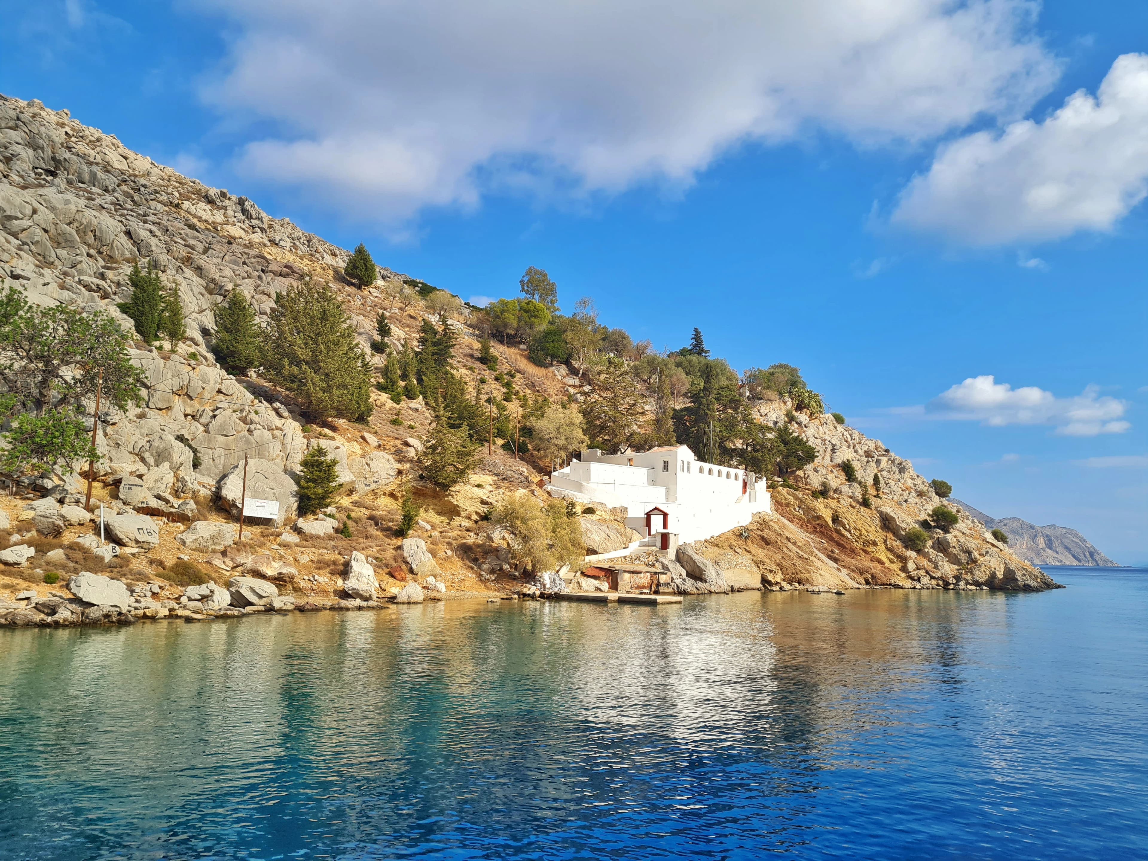 White building sits on a rocky shoreline.