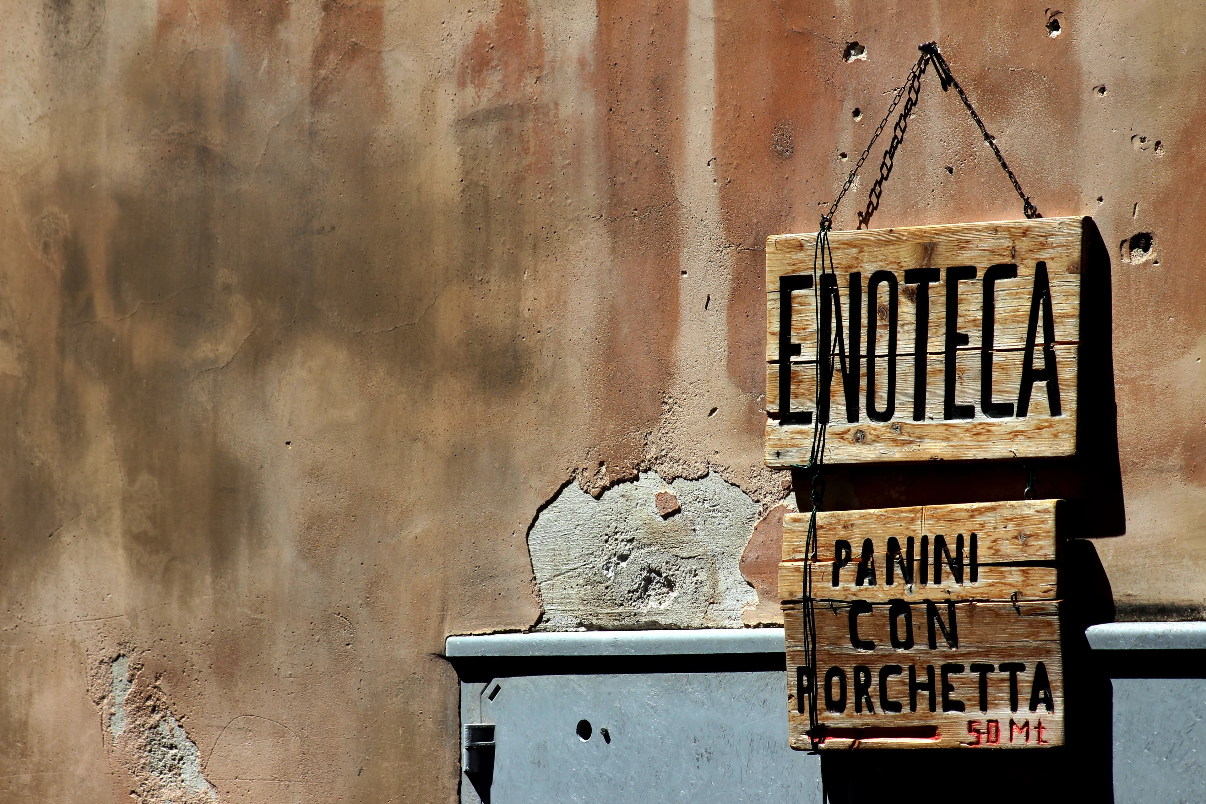 brown wooden signage on white concrete wall