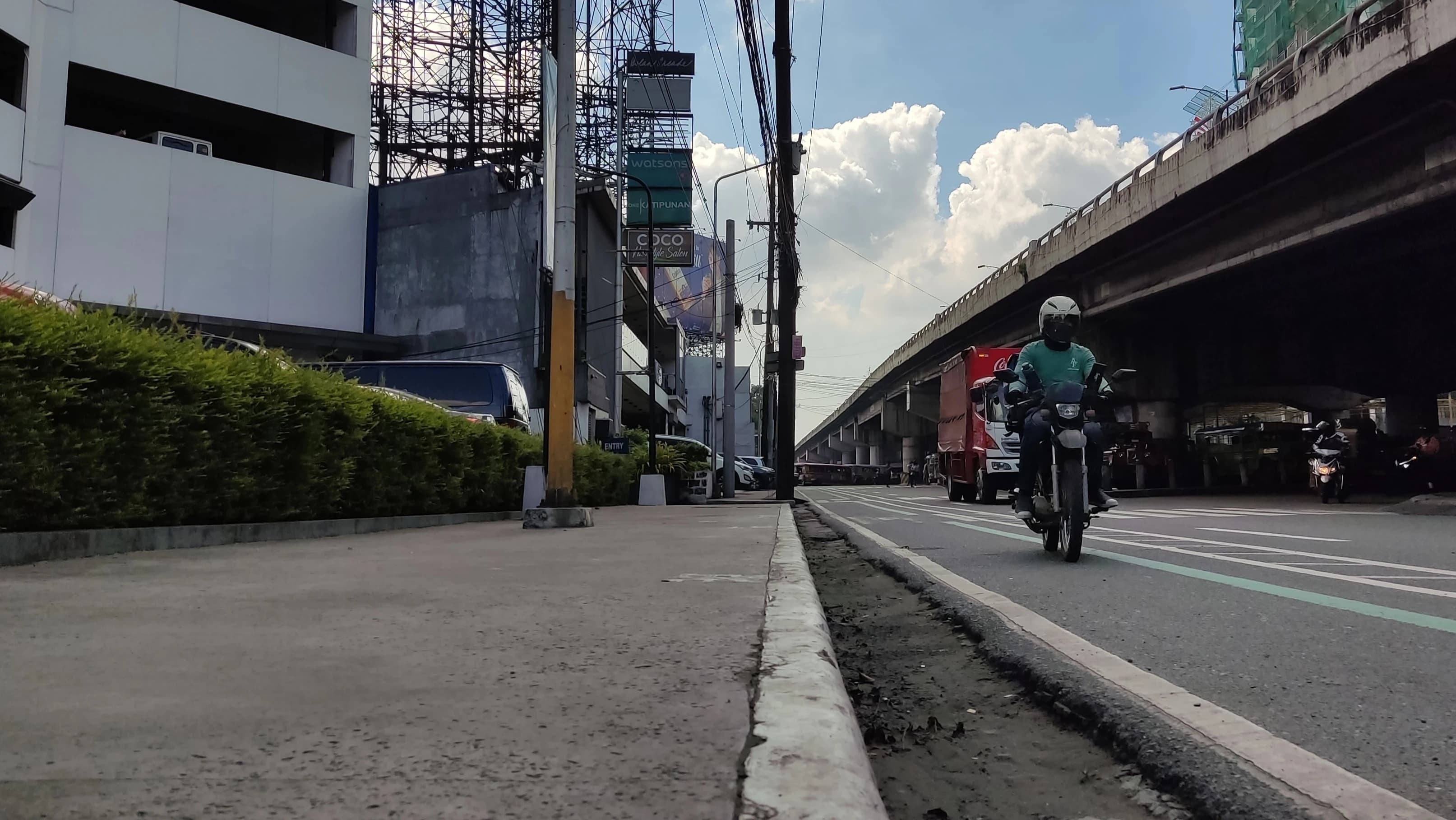 a man riding a motorcycle down a street under a bridge