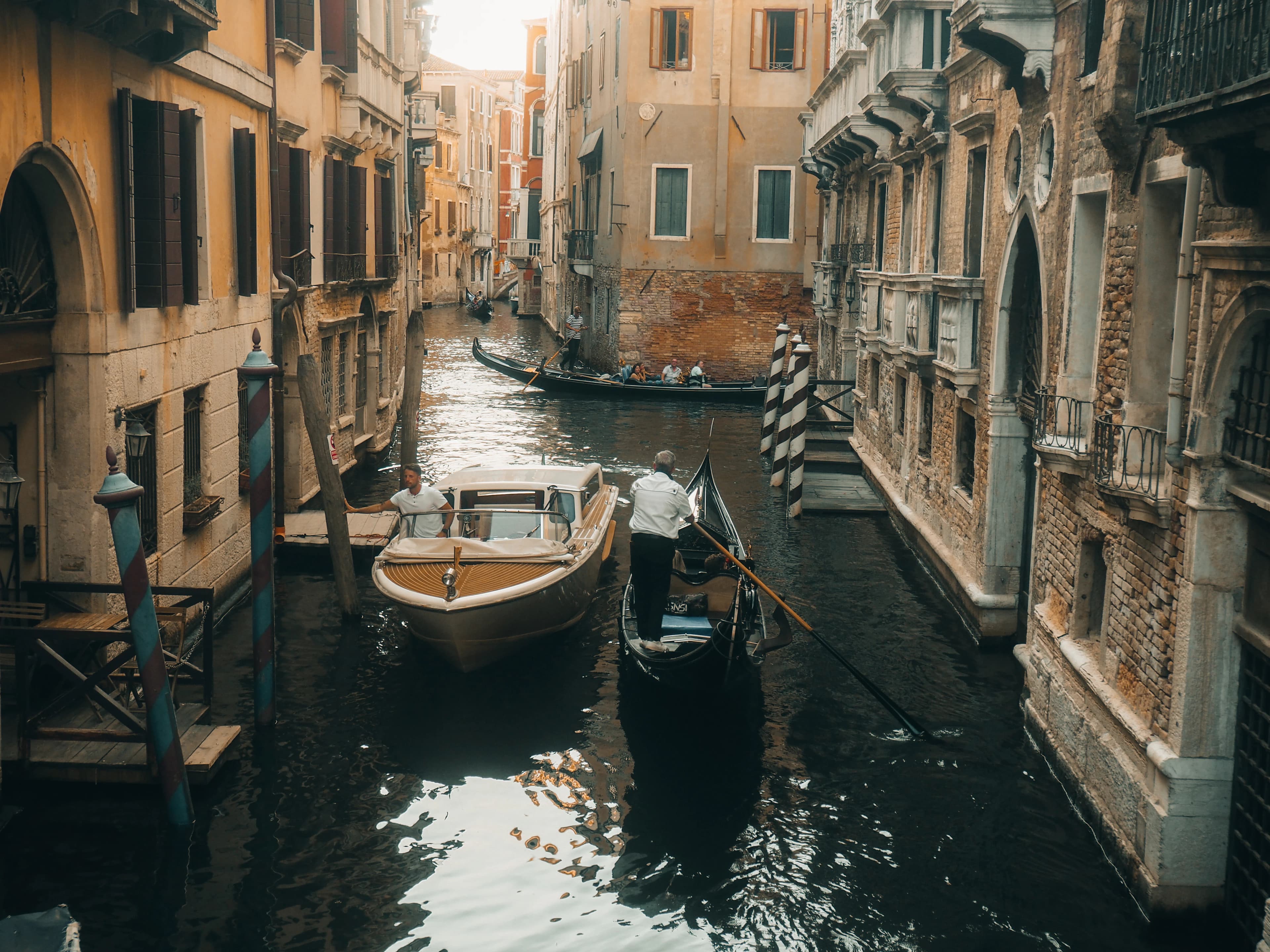Gondolier steers boat down a venetian canal.