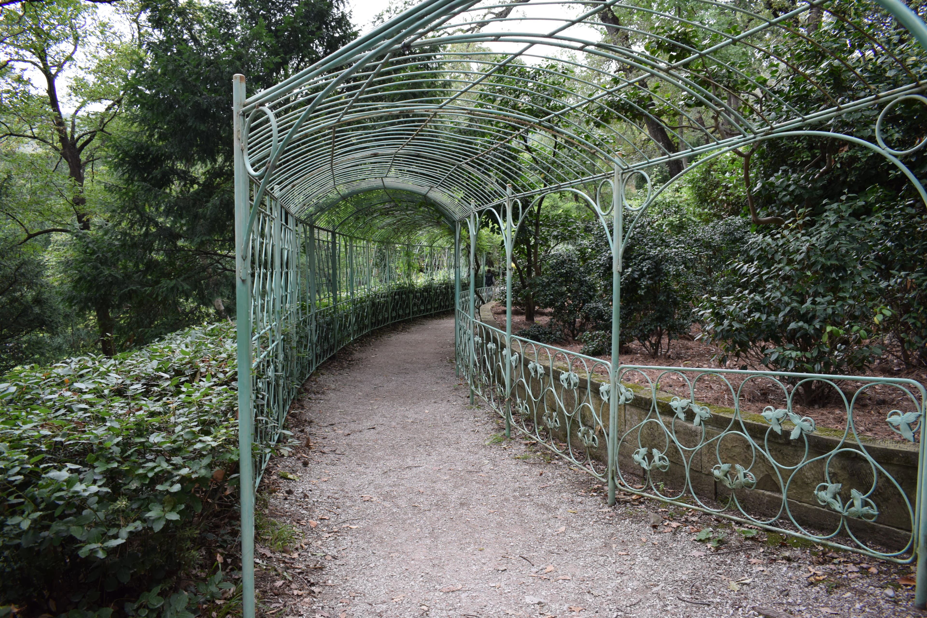 Green metal archway over a gravel path in a garden.