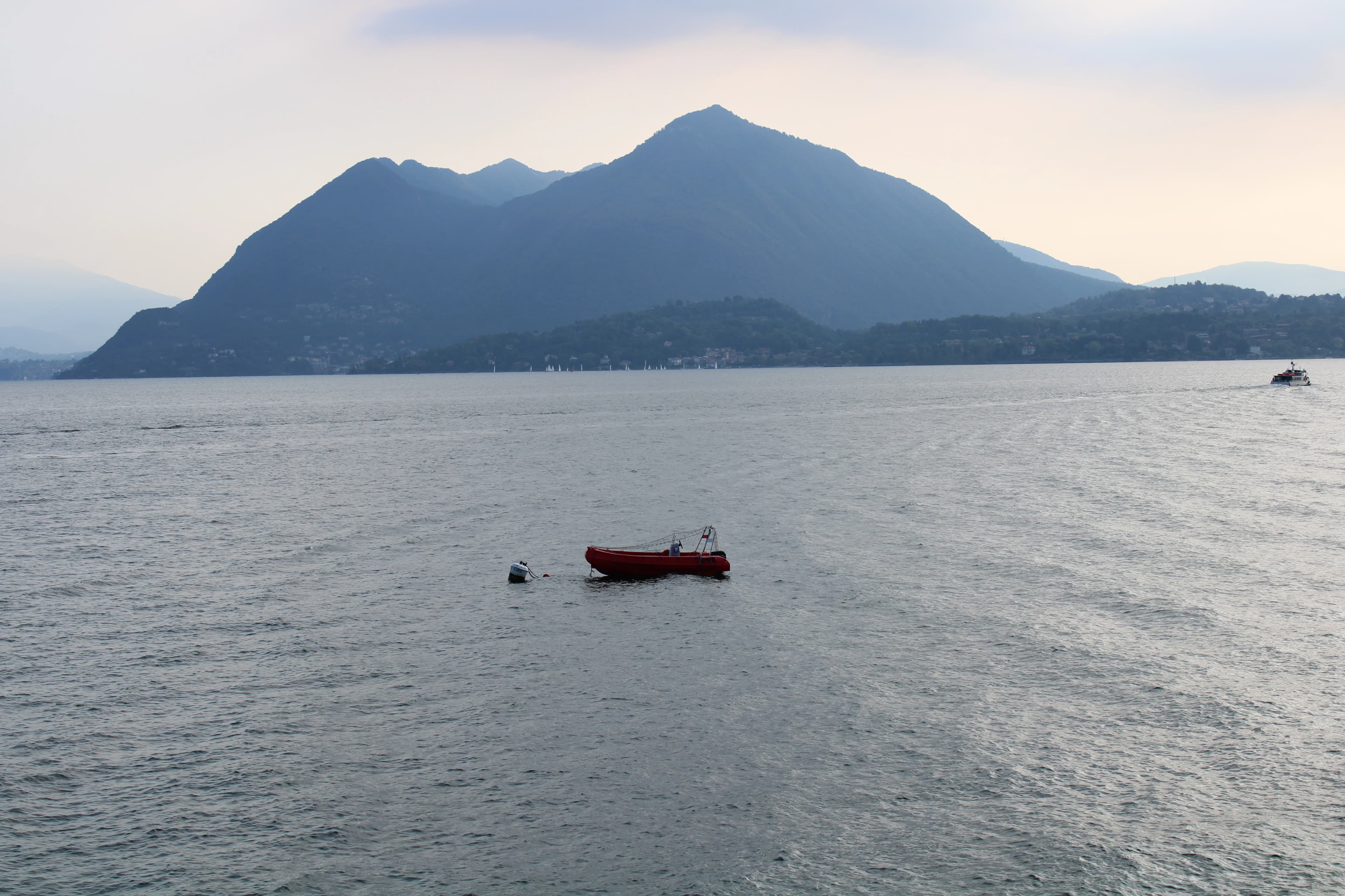 Small boat floats on calm lake with mountain background