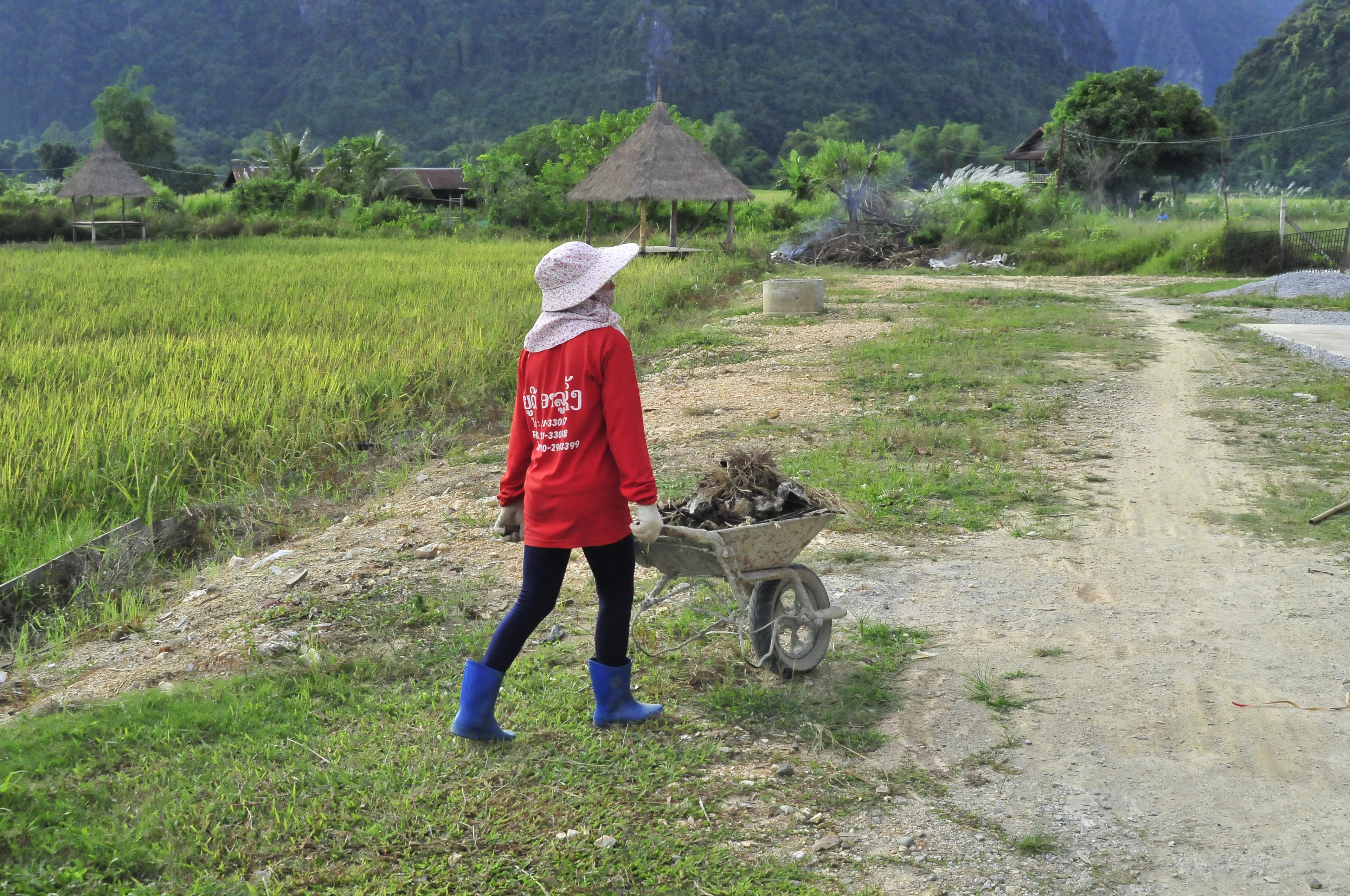 Person pushing a wheelbarrow on a dirt path