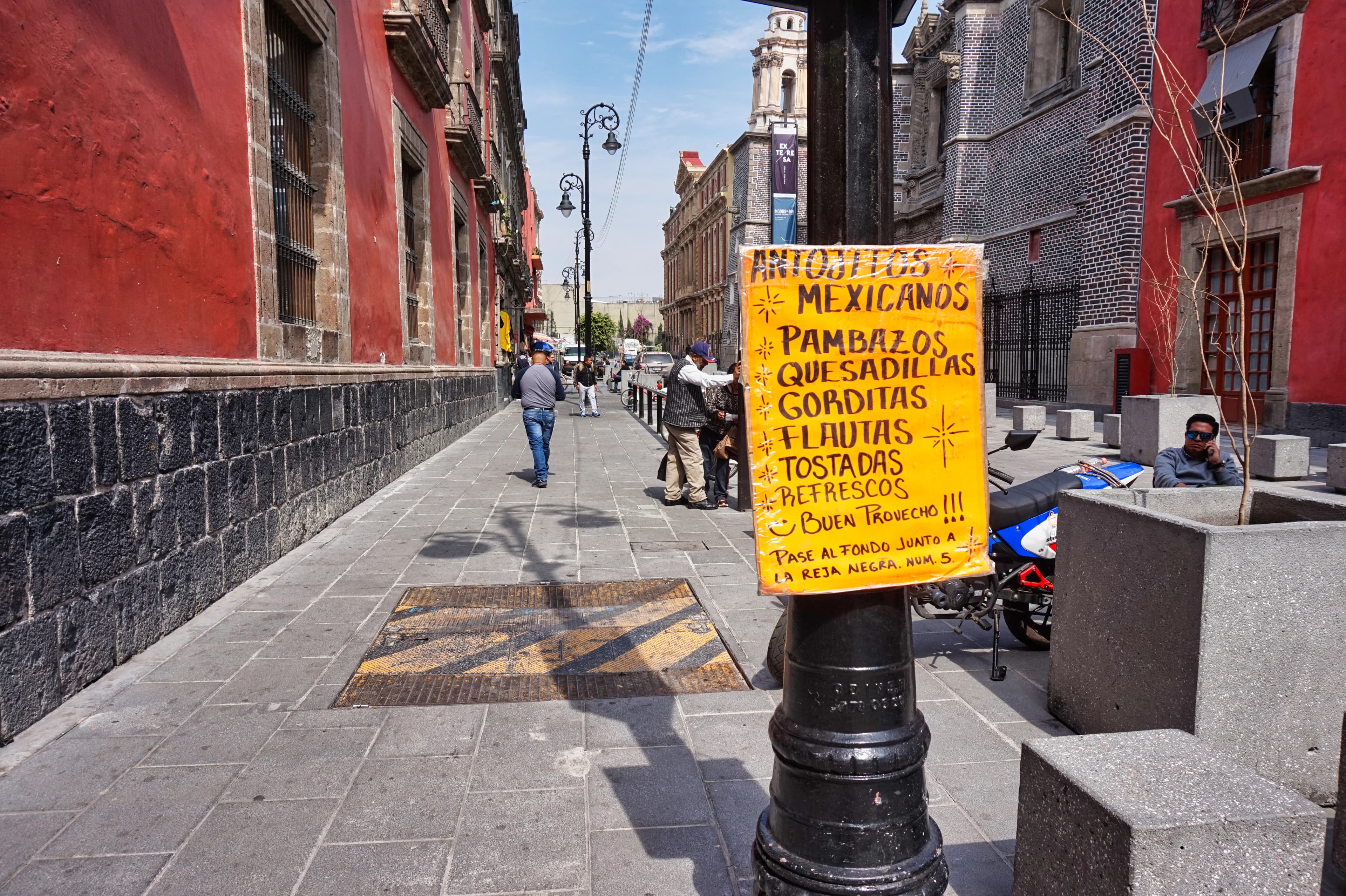 A yellow sign on a black pole on a city street