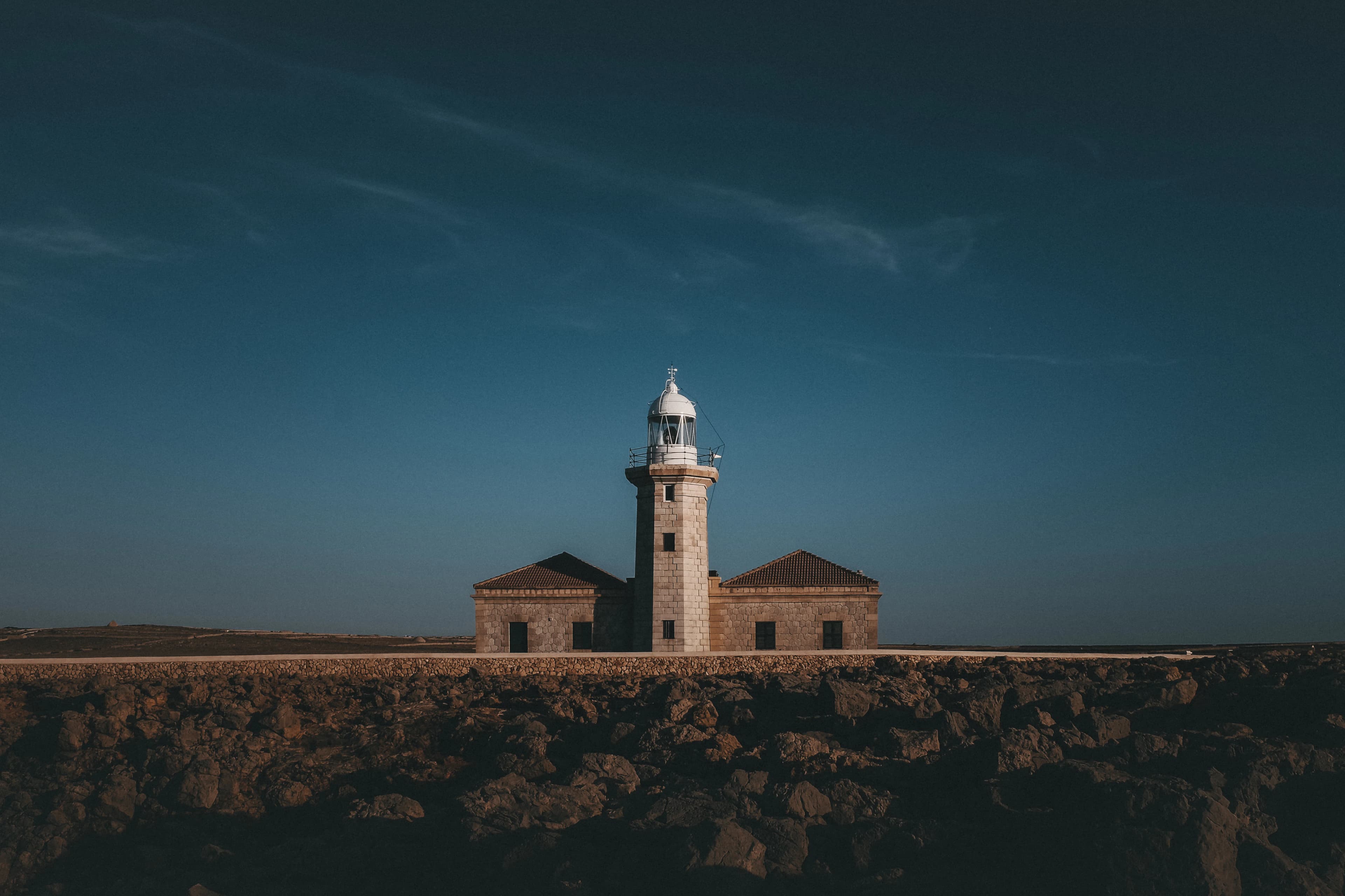 a lighthouse on top of a cliff under a blue sky