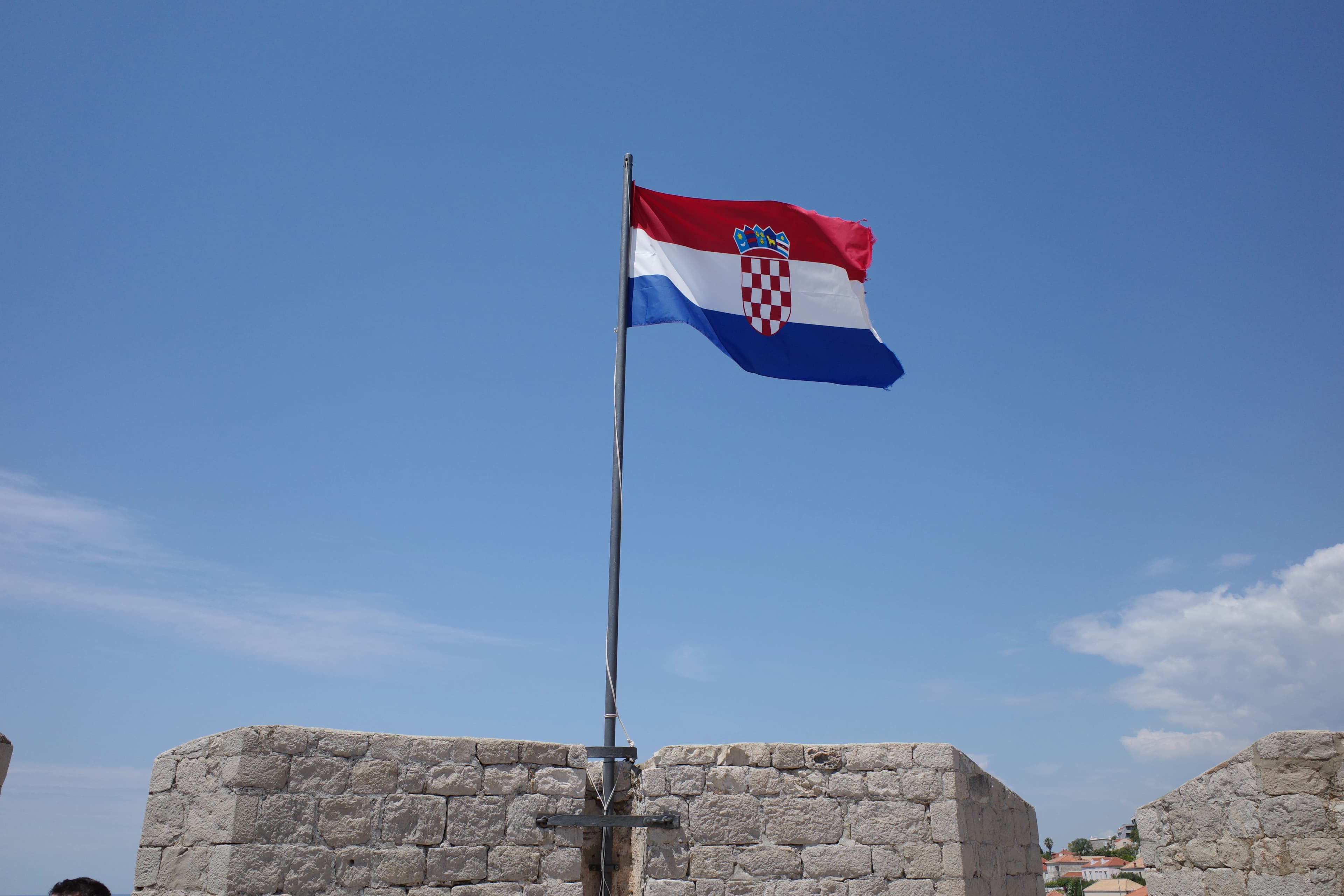 A flag flying in front of a stone wall