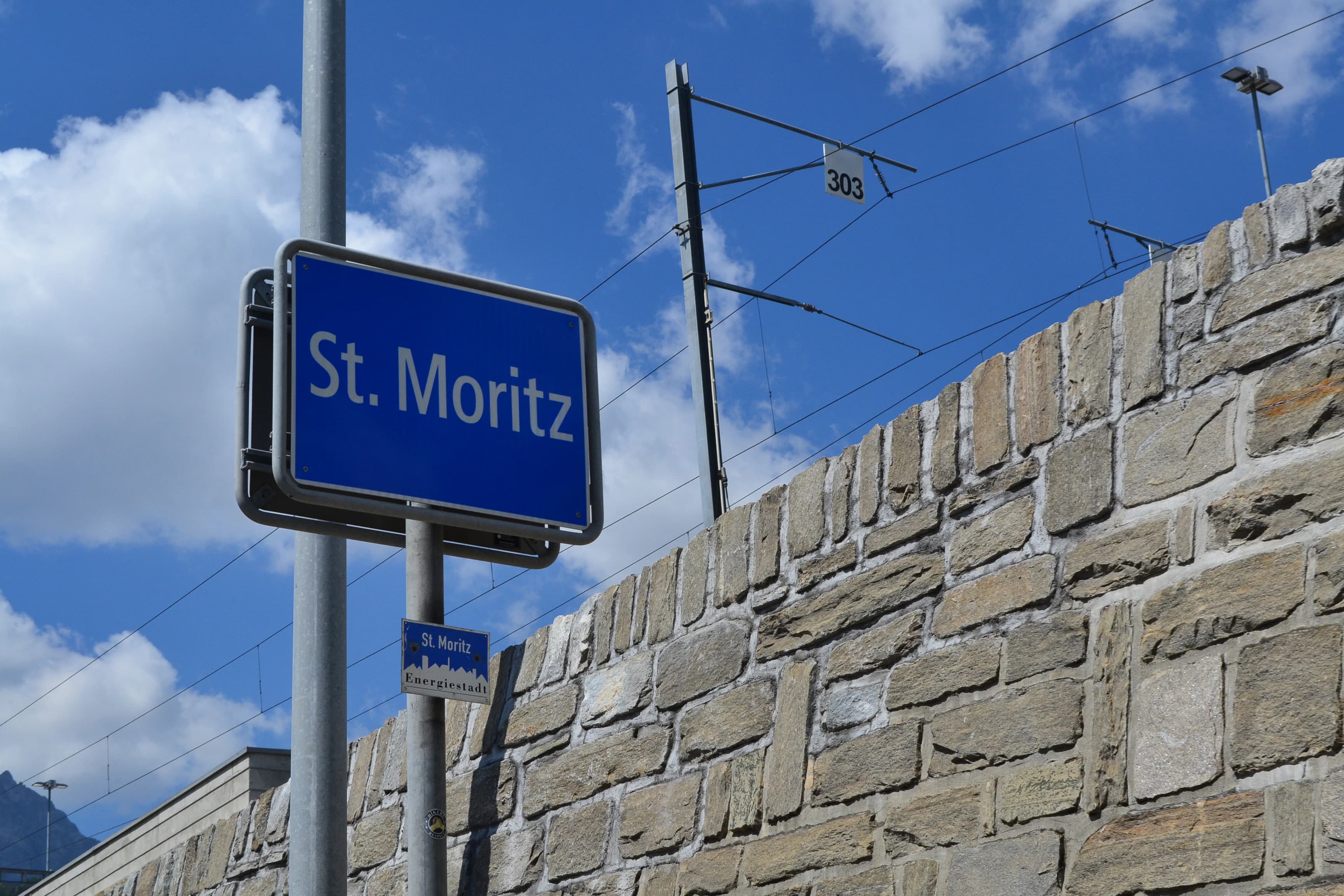 a blue street sign sitting on the side of a brick wall