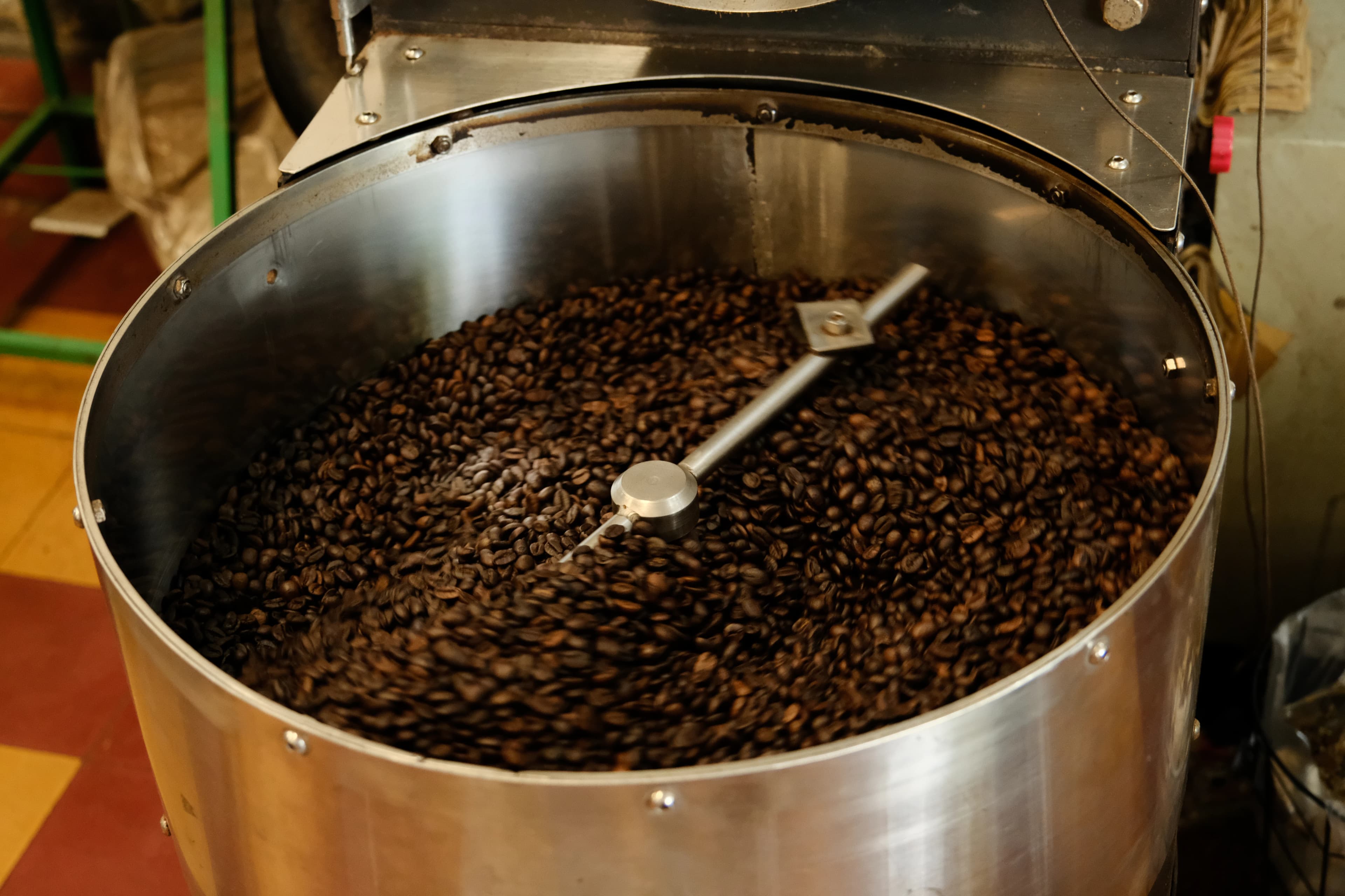 Coffee beans roasting inside a metal container.