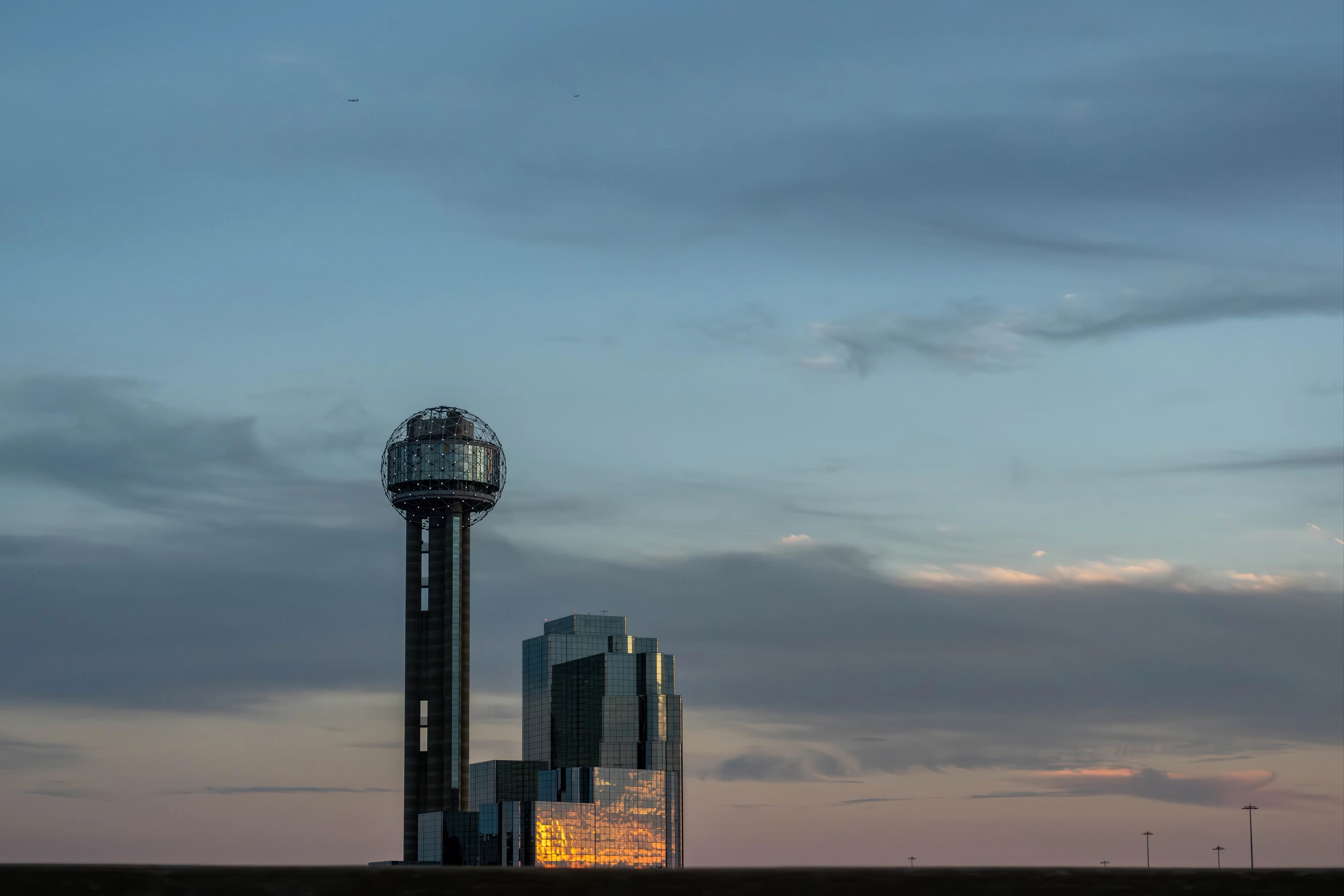 Modern buildings with a tall observation tower at sunset.
