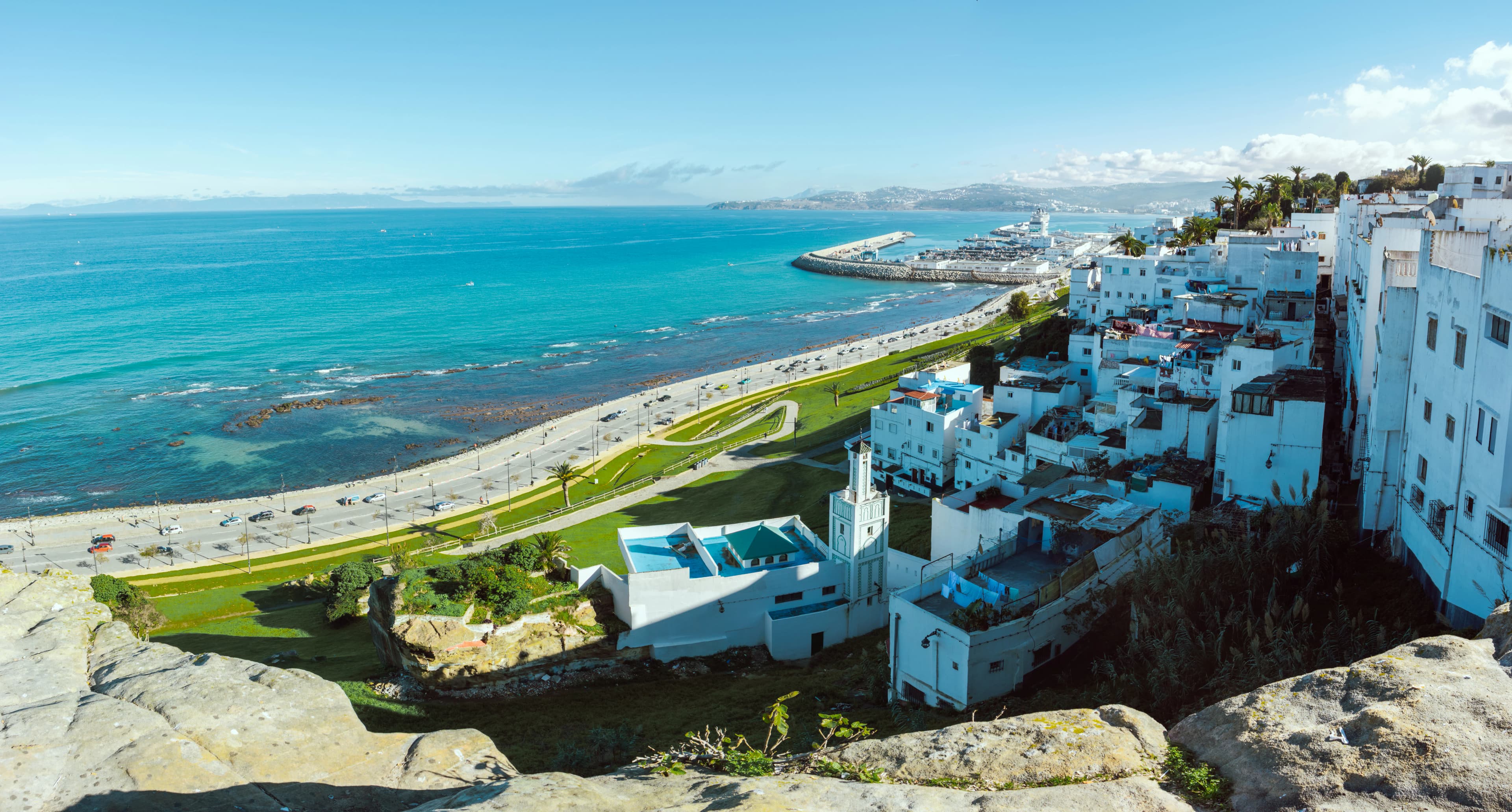 White buildings overlook a coastal town and blue ocean.