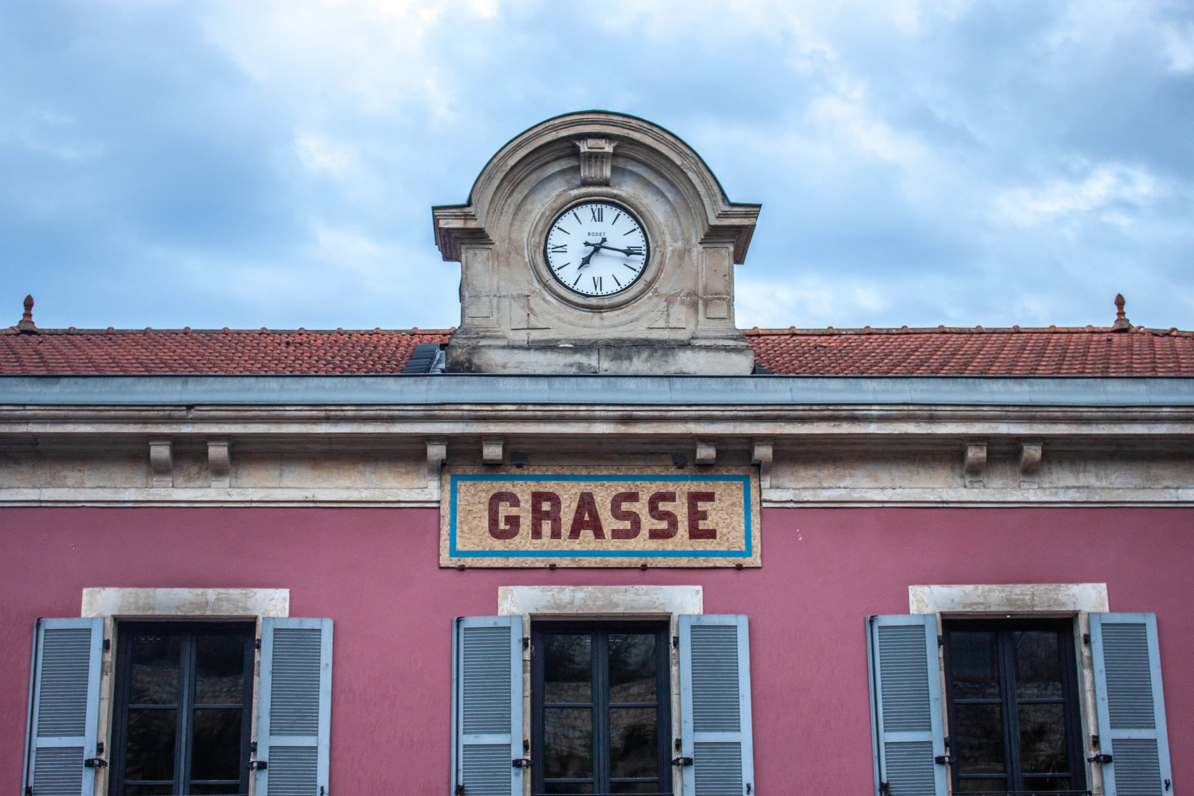 Pink building with grasse sign and clock