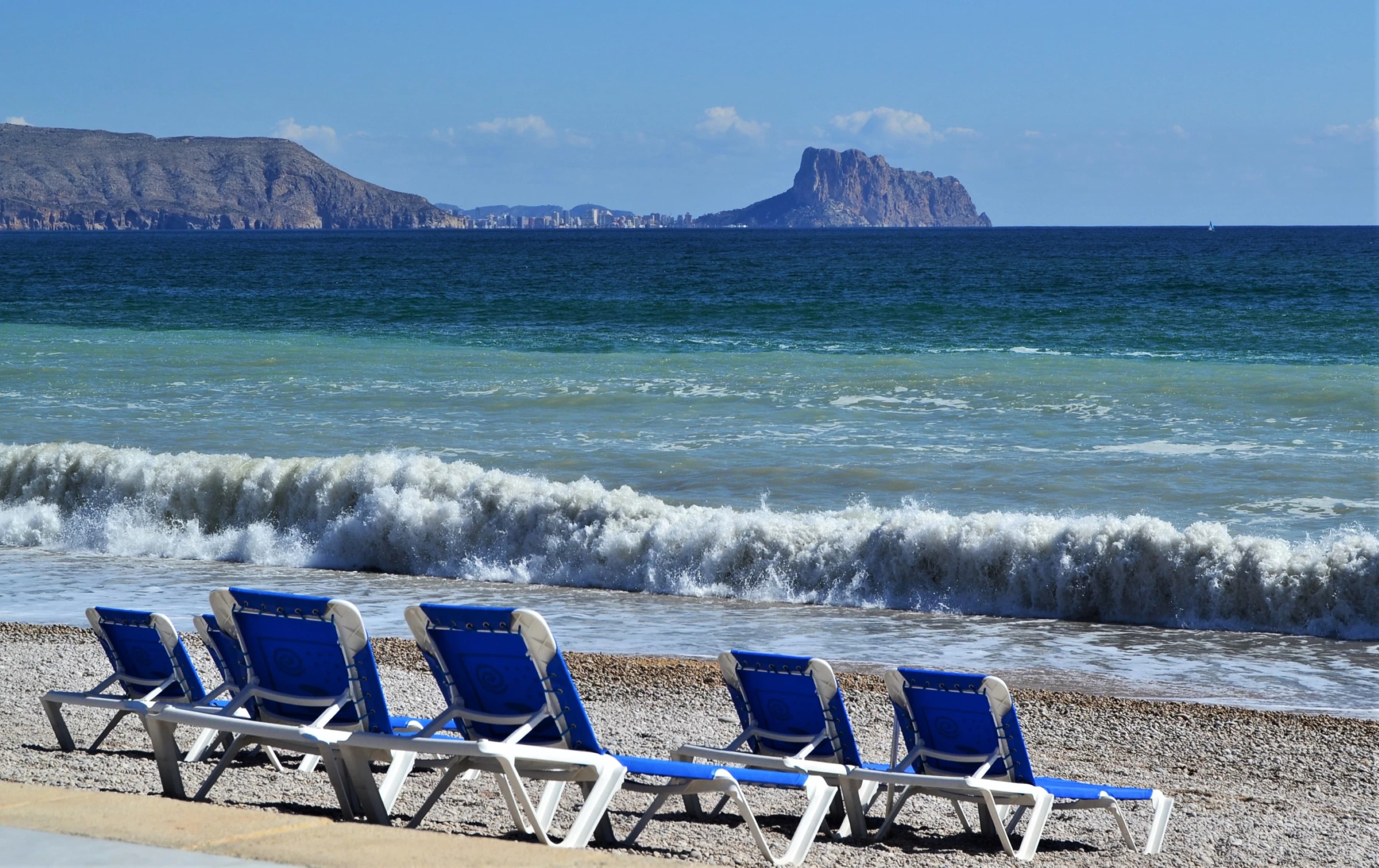 A row of beach chairs sitting on top of a sandy beach