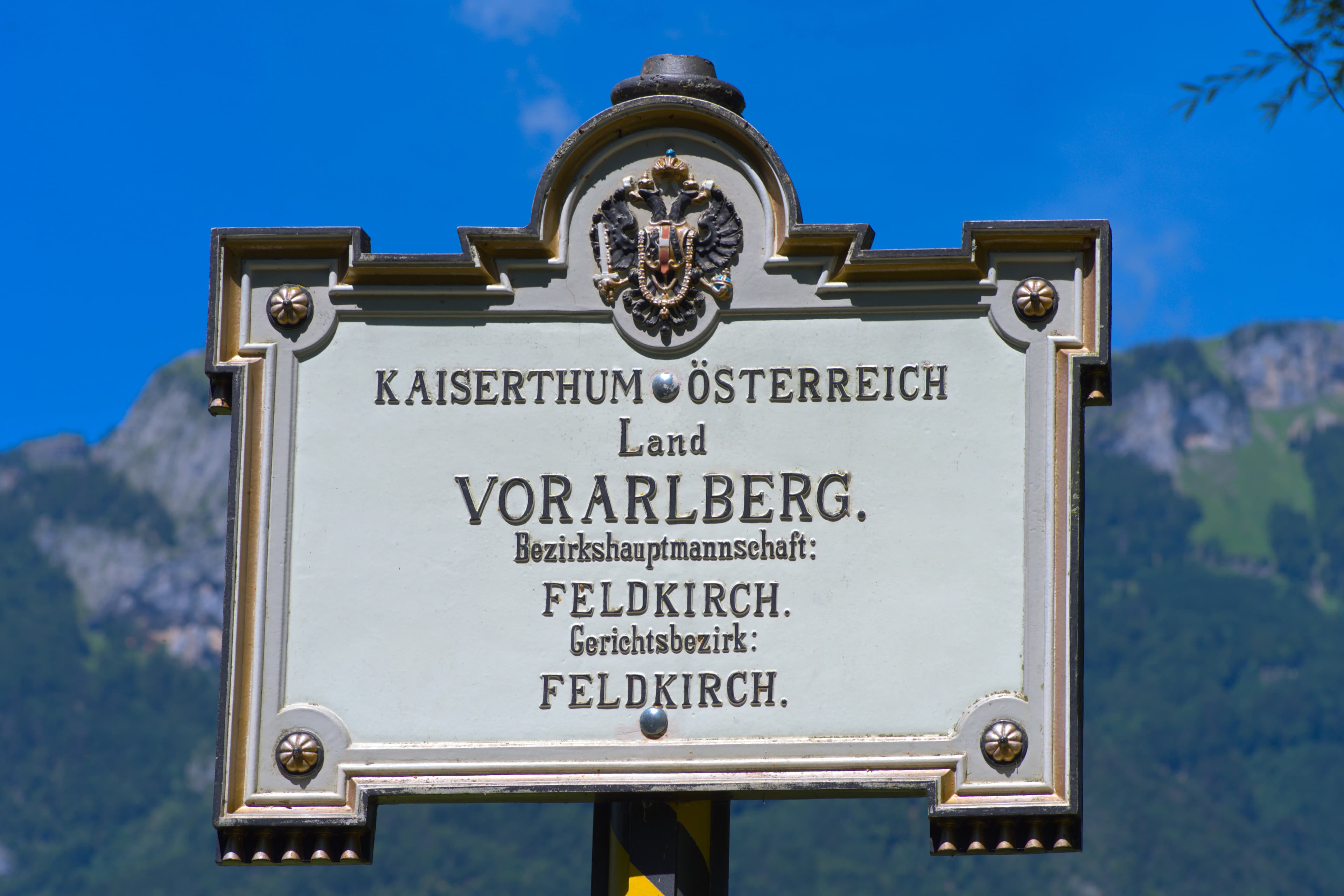 A sign in front of a mountain with a blue sky in the background