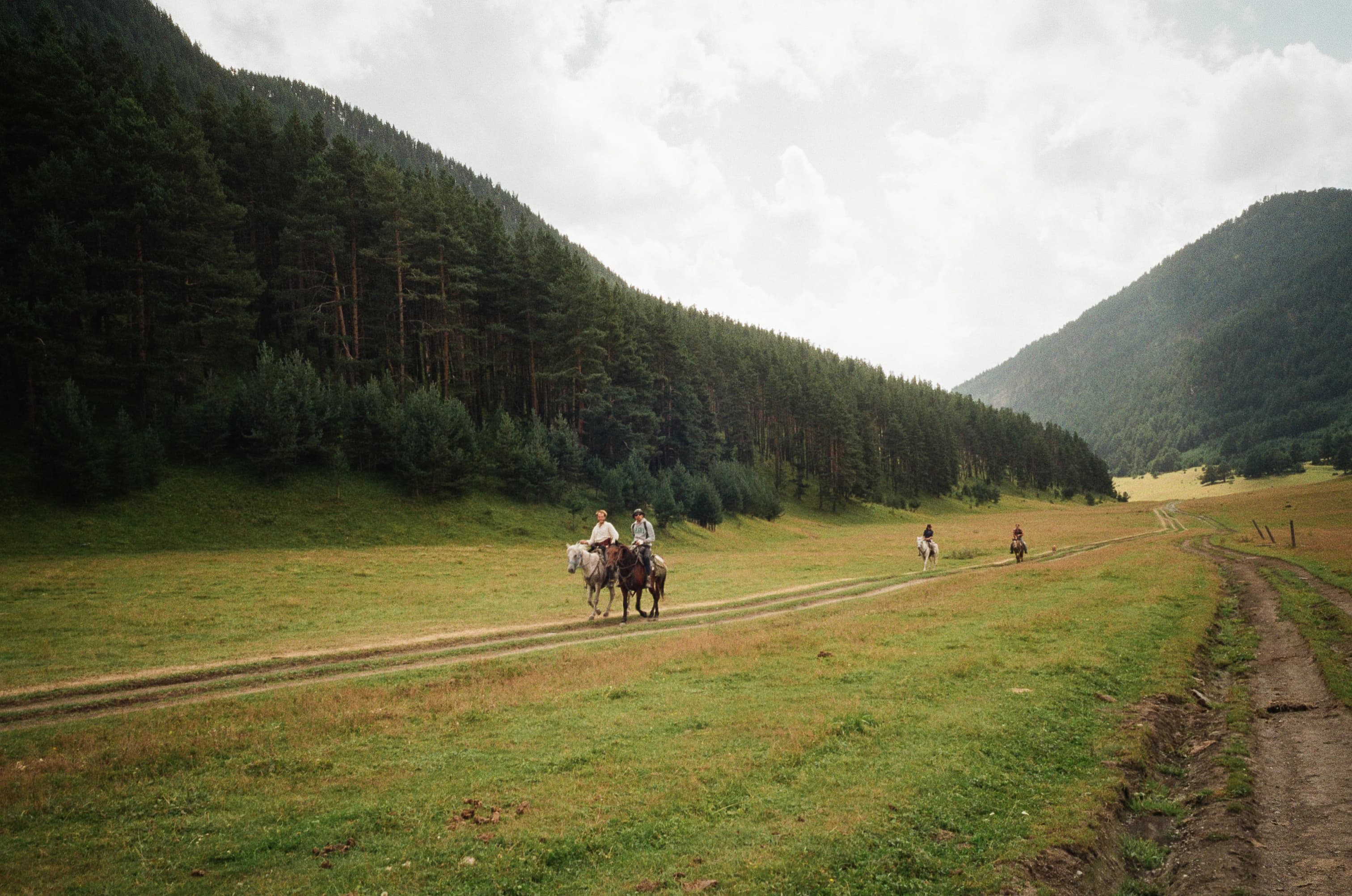 Two riders are enjoying a horseback ride in the valley.