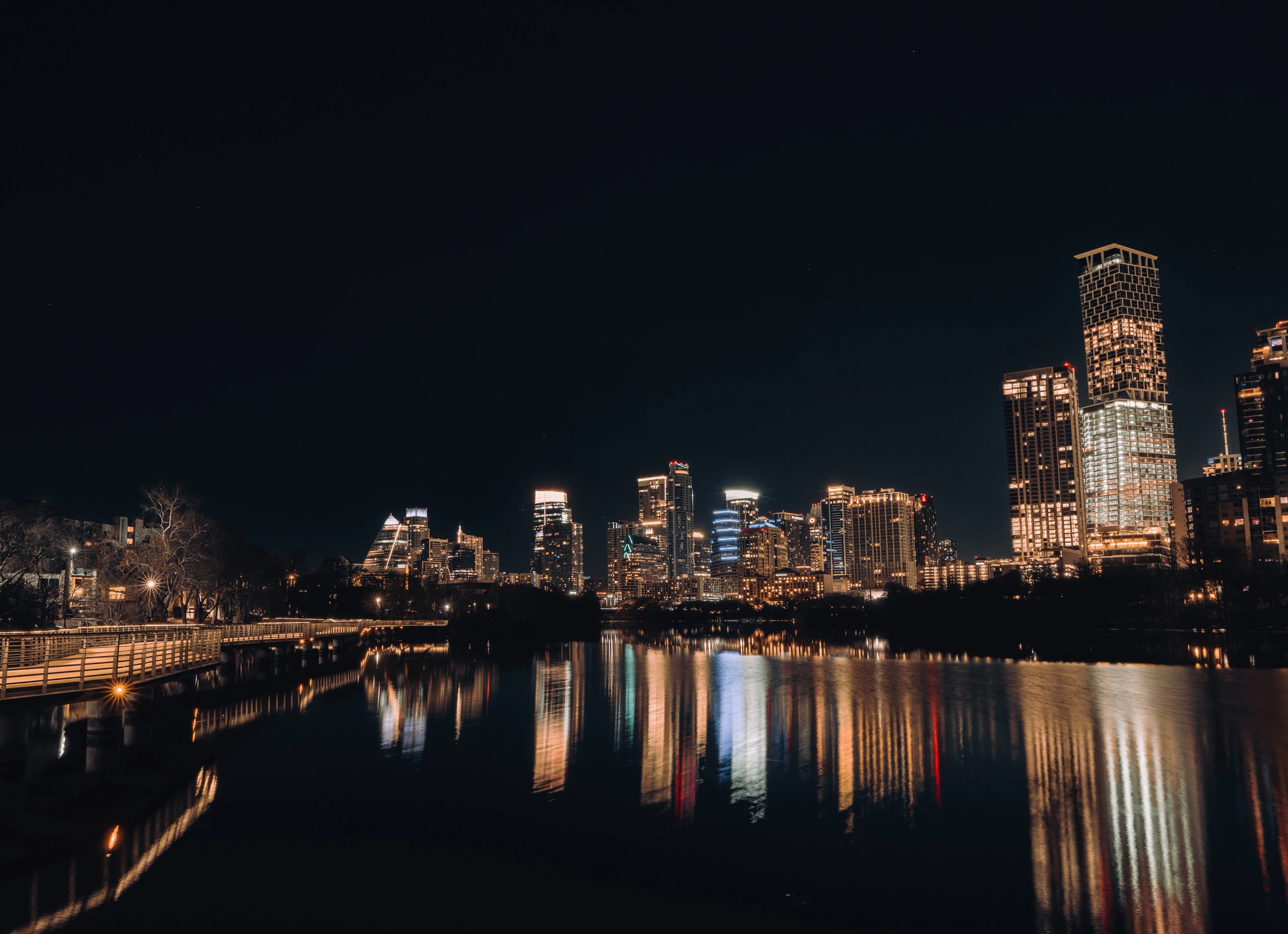 City skyline illuminated at night with water reflections.