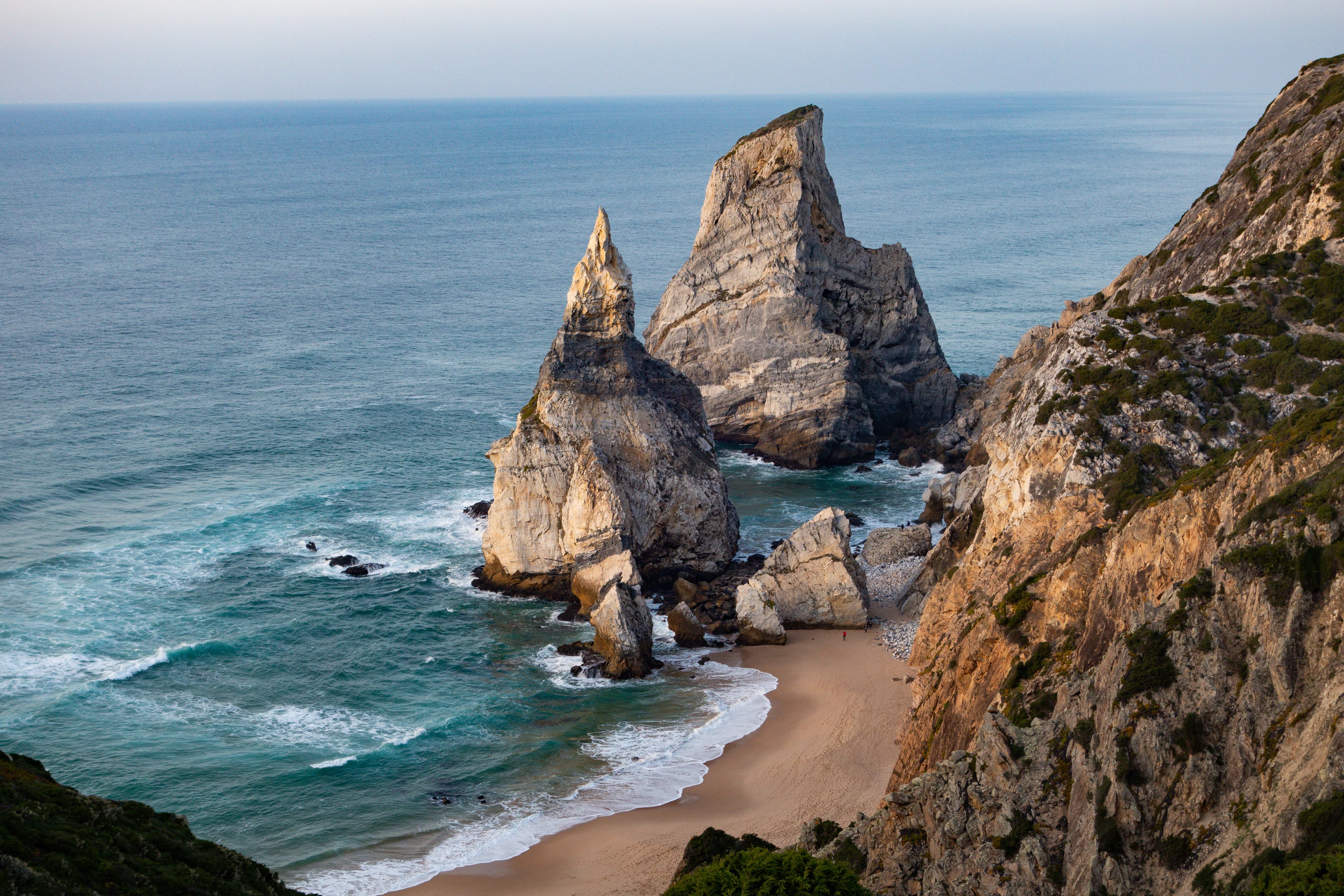a view of a beach with two large rocks sticking out of the water