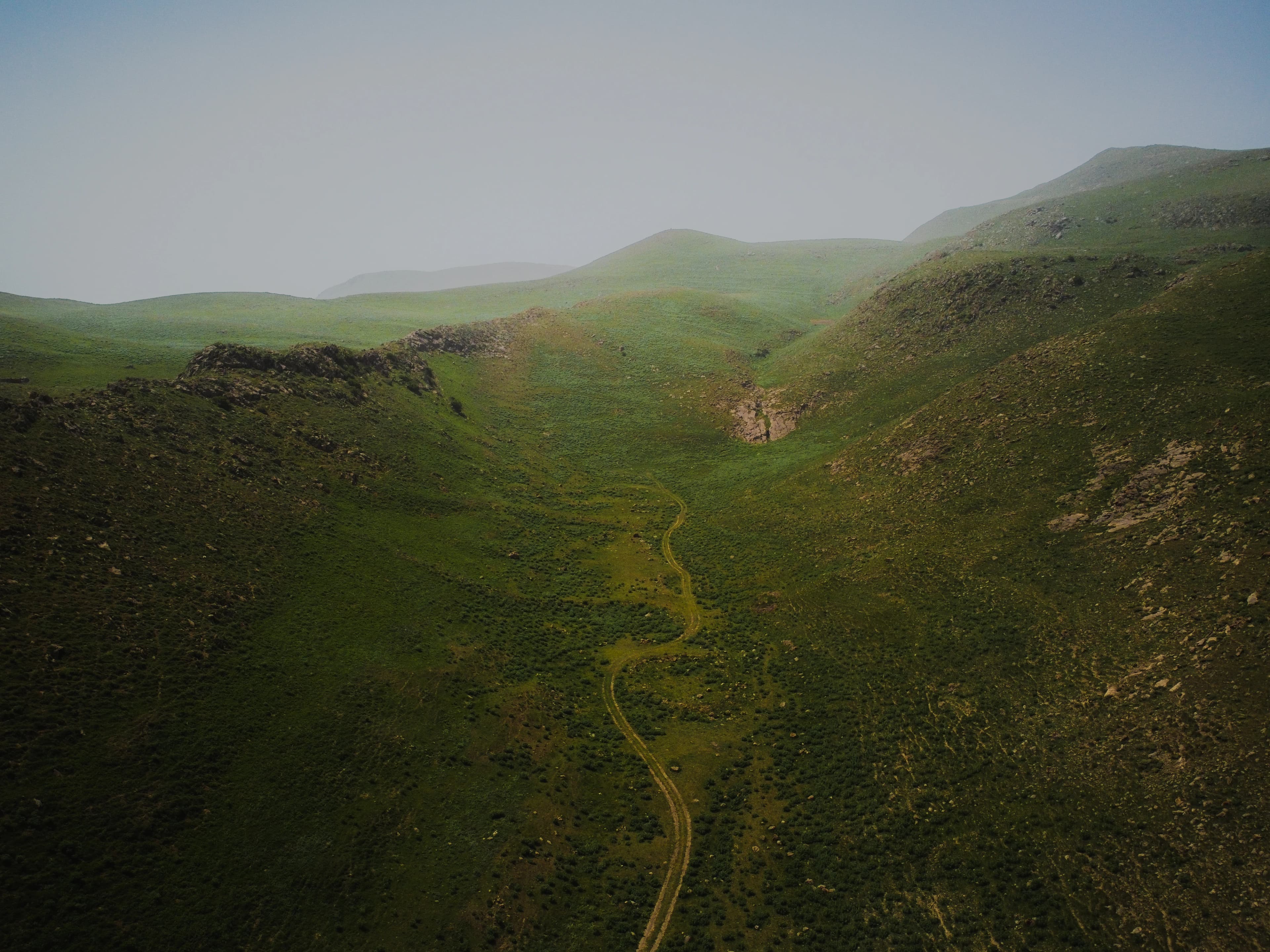 an aerial view of a hilly area with a winding road