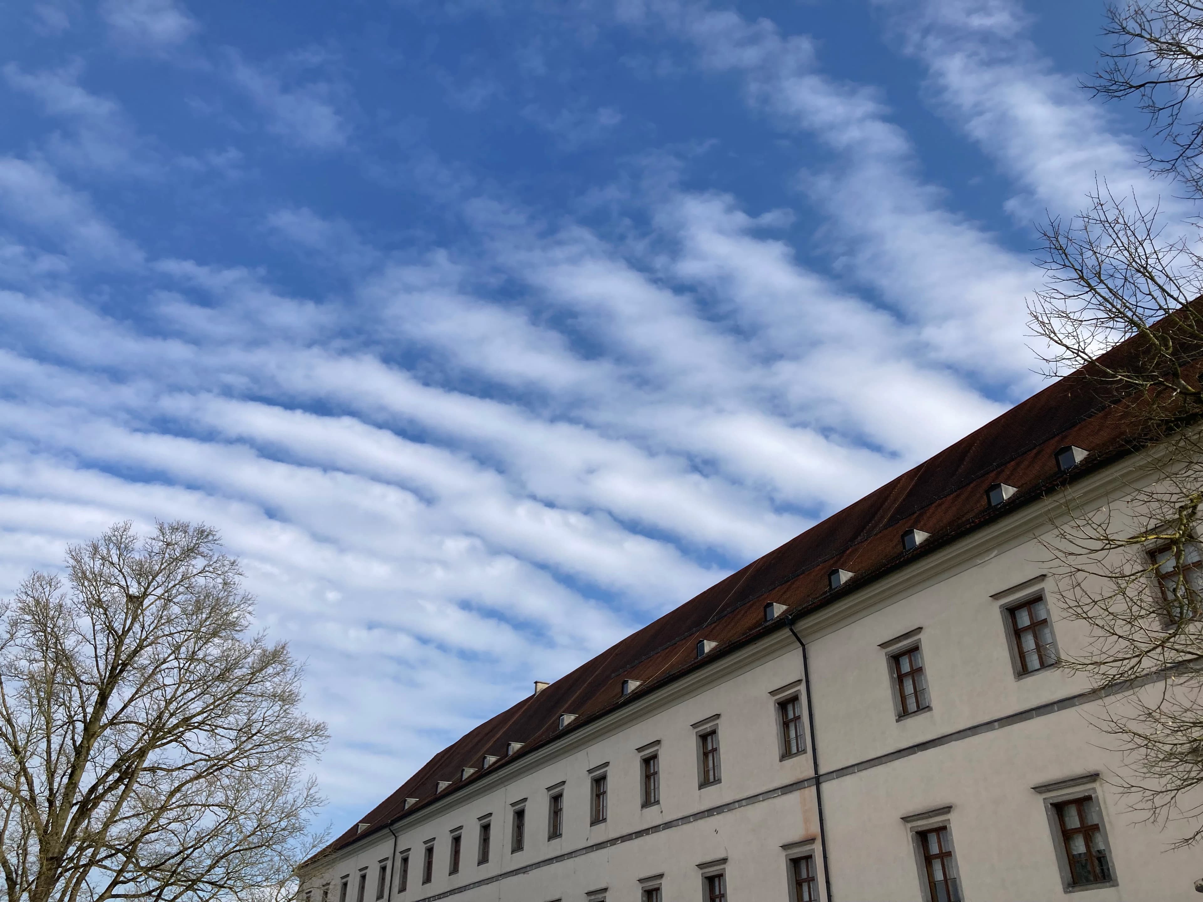 a white building with a brown roof under a cloudy blue sky
