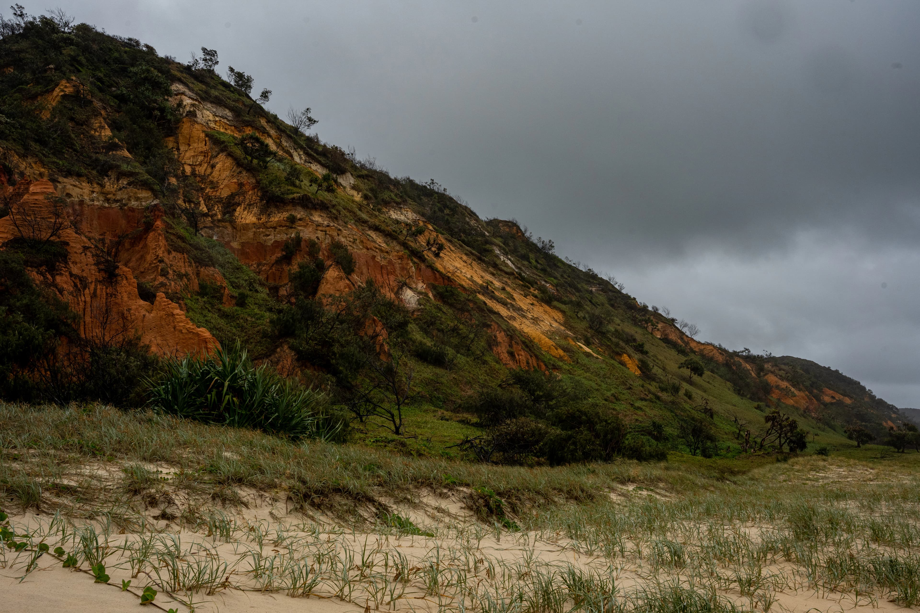 a hill with a grassy area next to it on a cloudy day