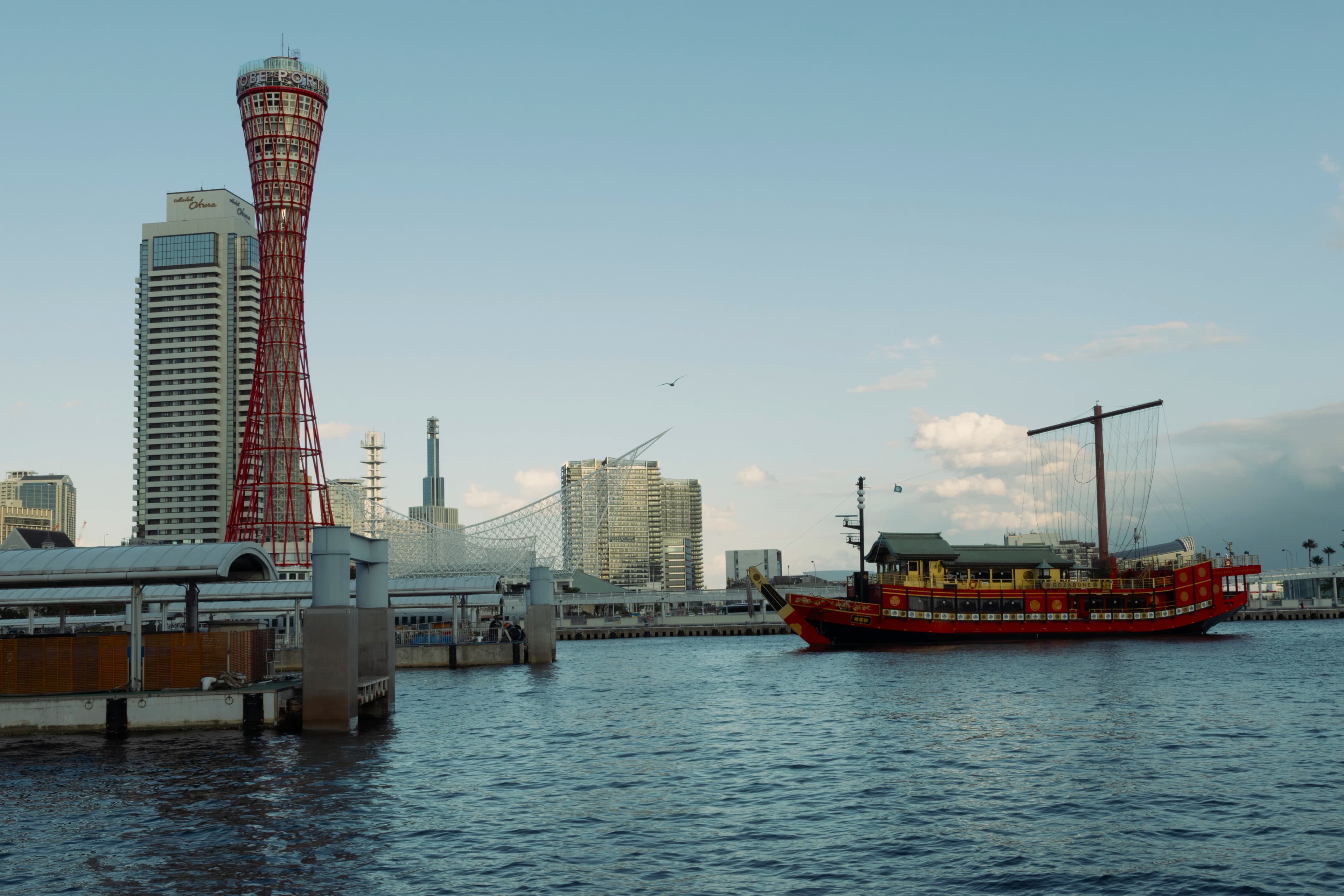 A traditional boat sails in a bustling harbor.