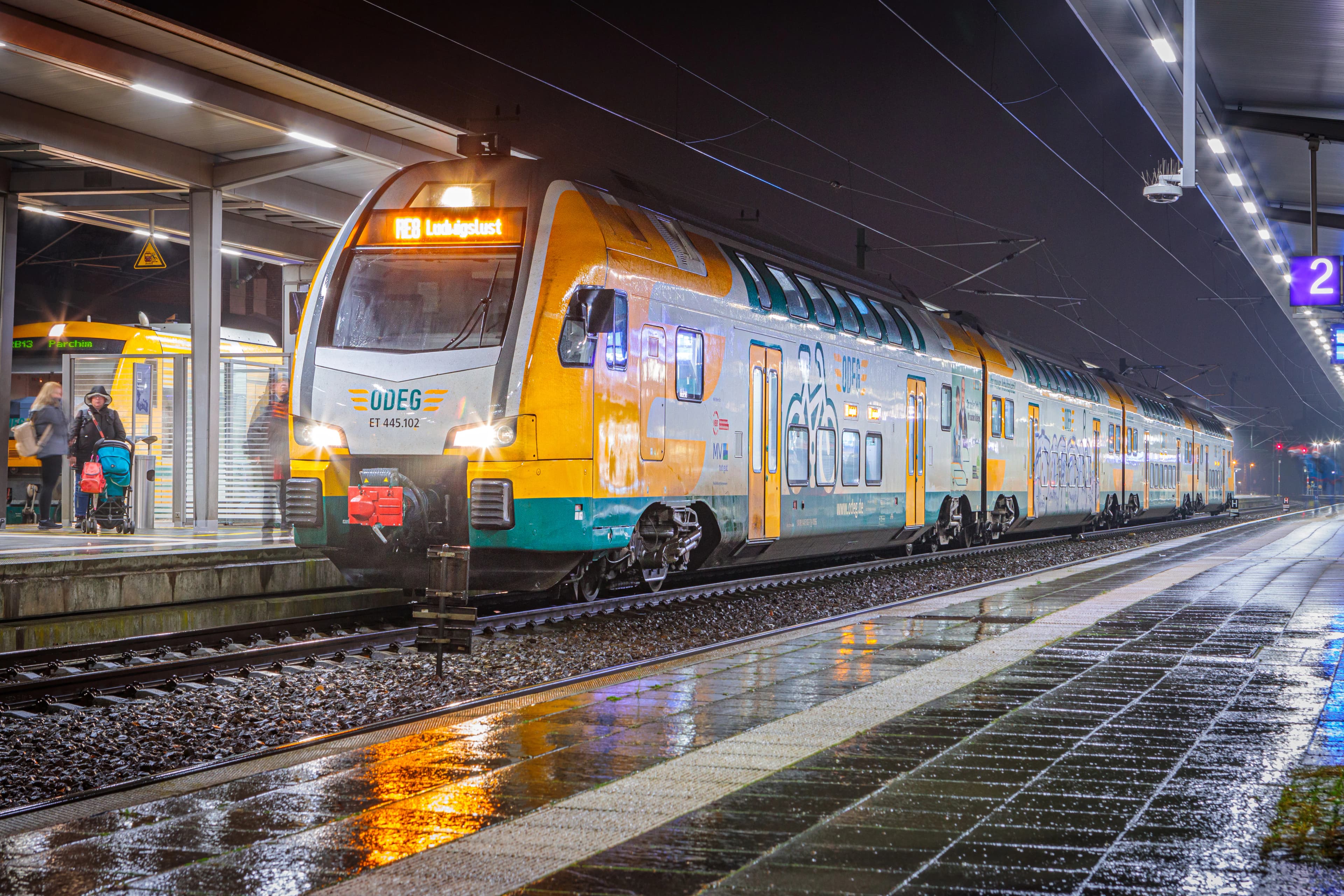 A yellow and green train pulling into a train station