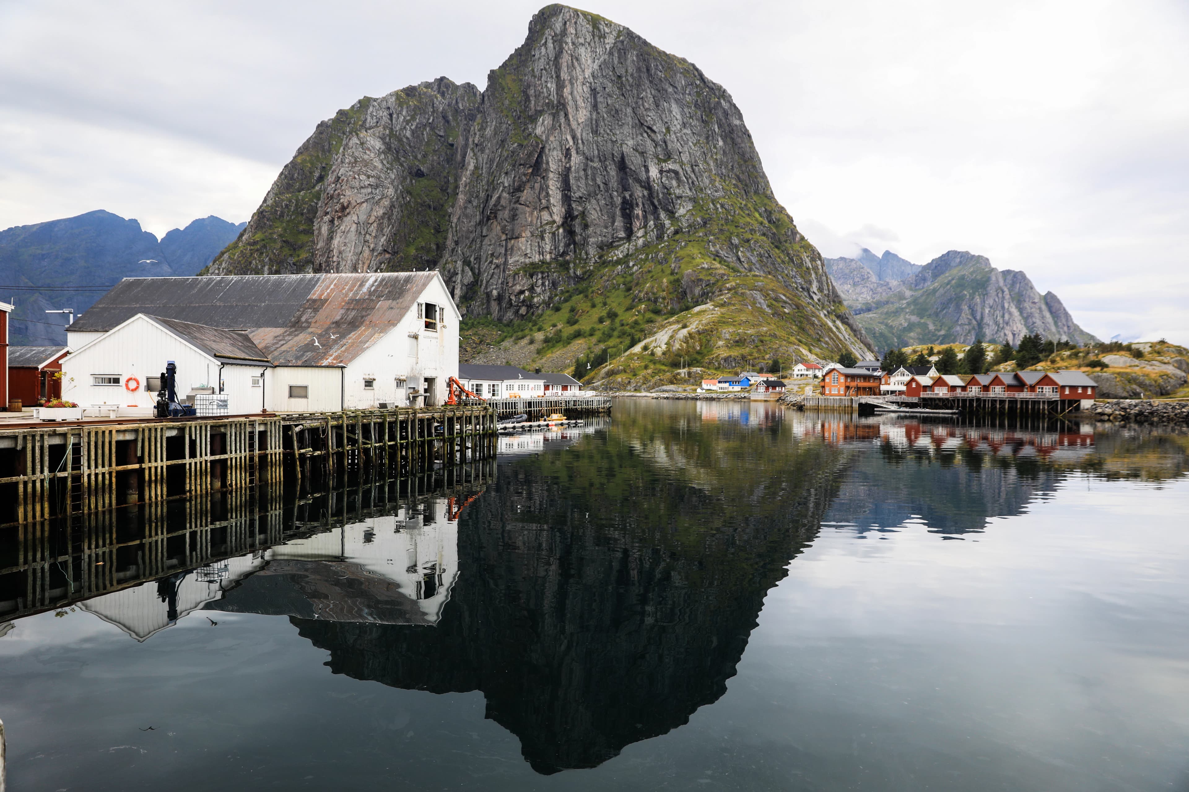 a body of water with buildings and mountains in the background