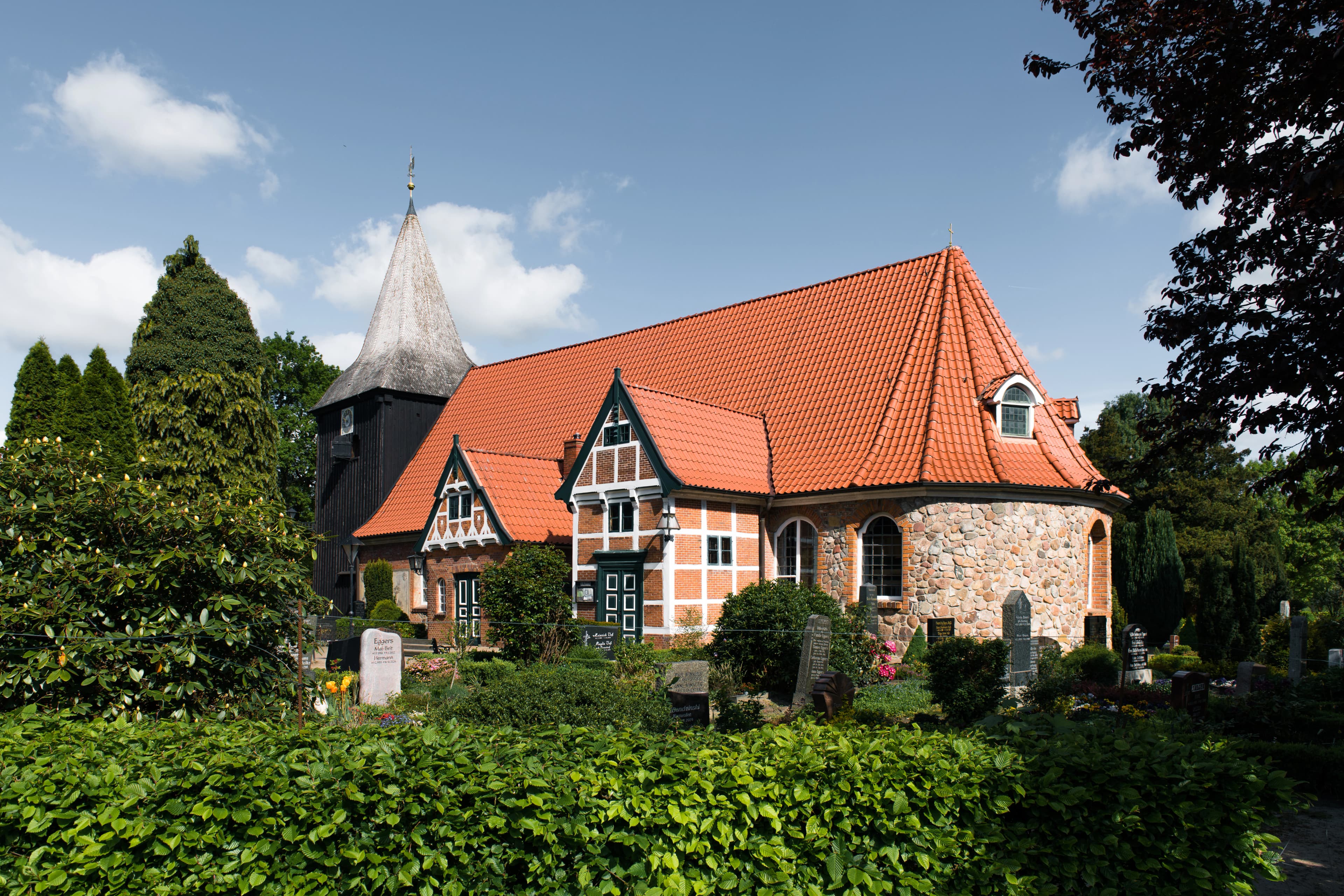 Historic church with red roof and steeple surrounded by trees