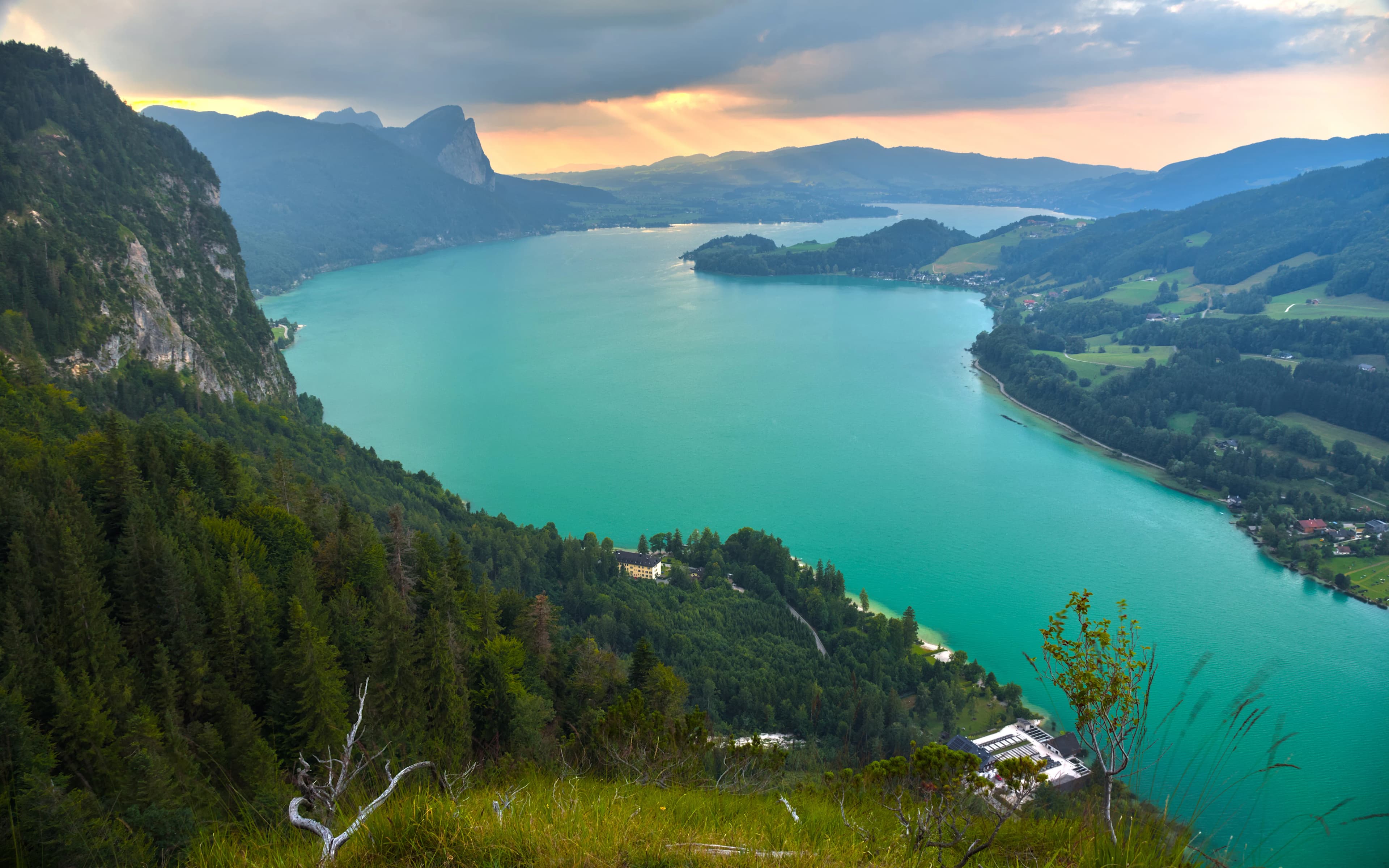 Turquoise lake surrounded by green mountains at sunset