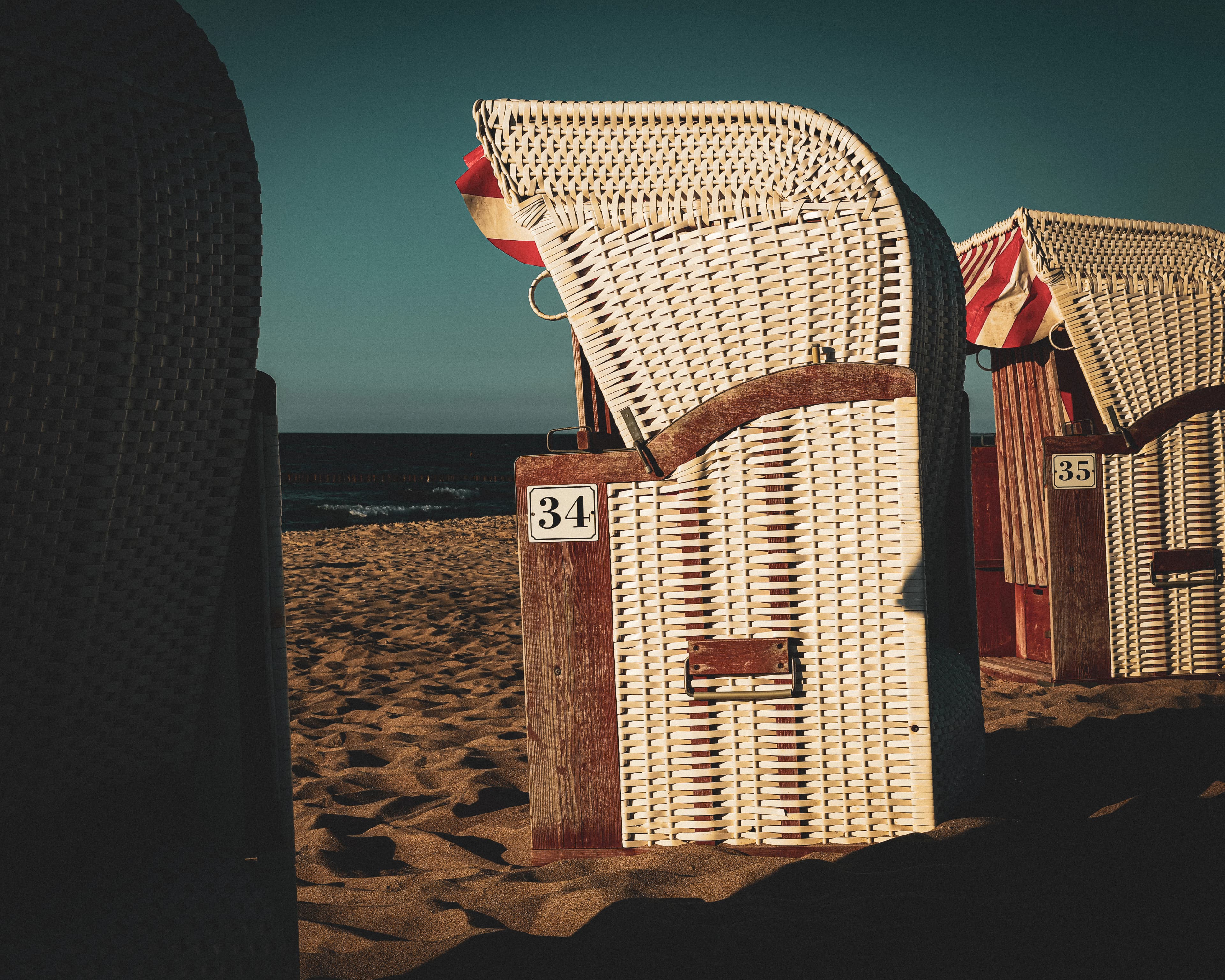 a couple of chairs sitting on top of a sandy beach