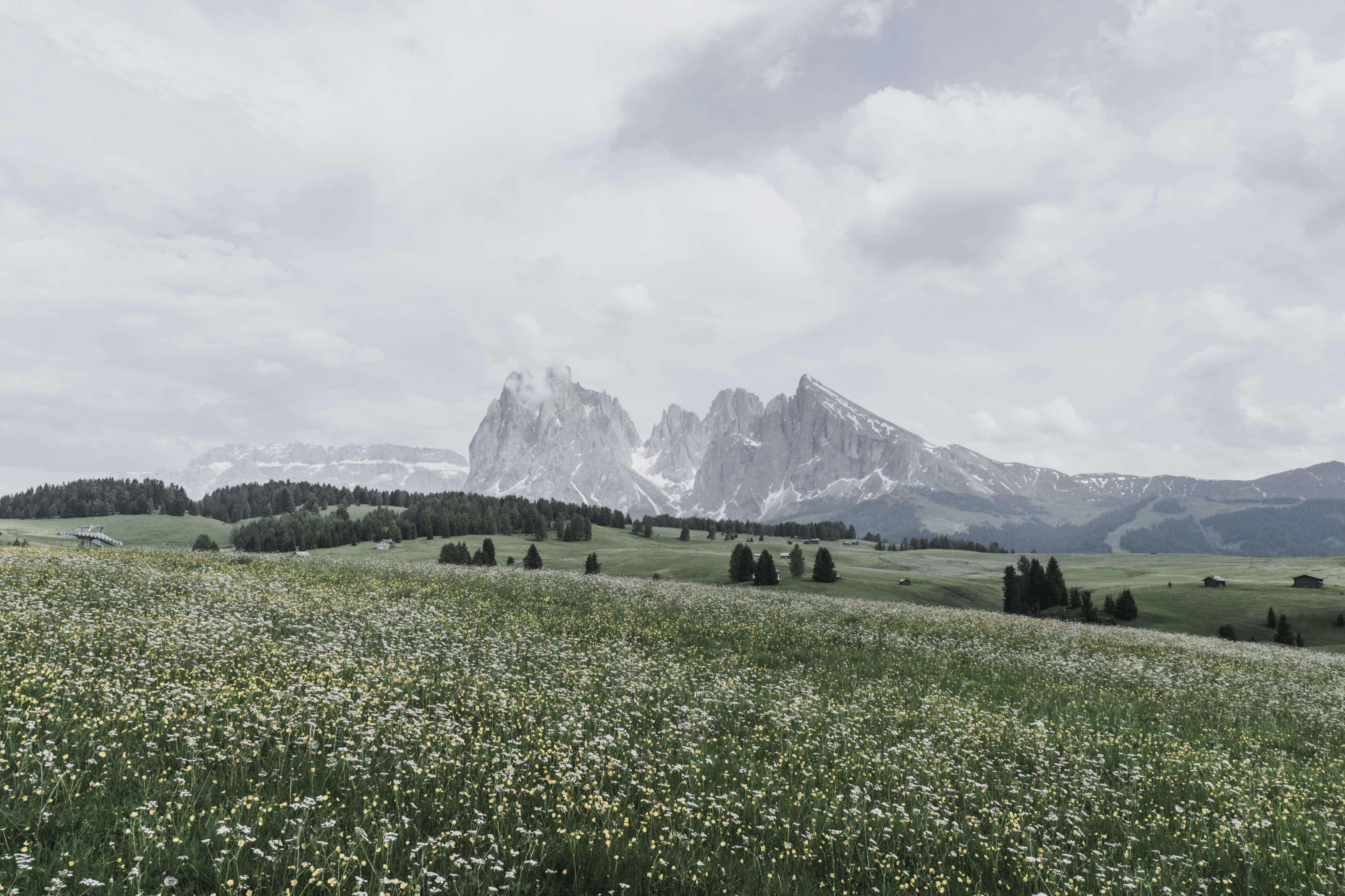 green grass field near mountain under white clouds during daytime