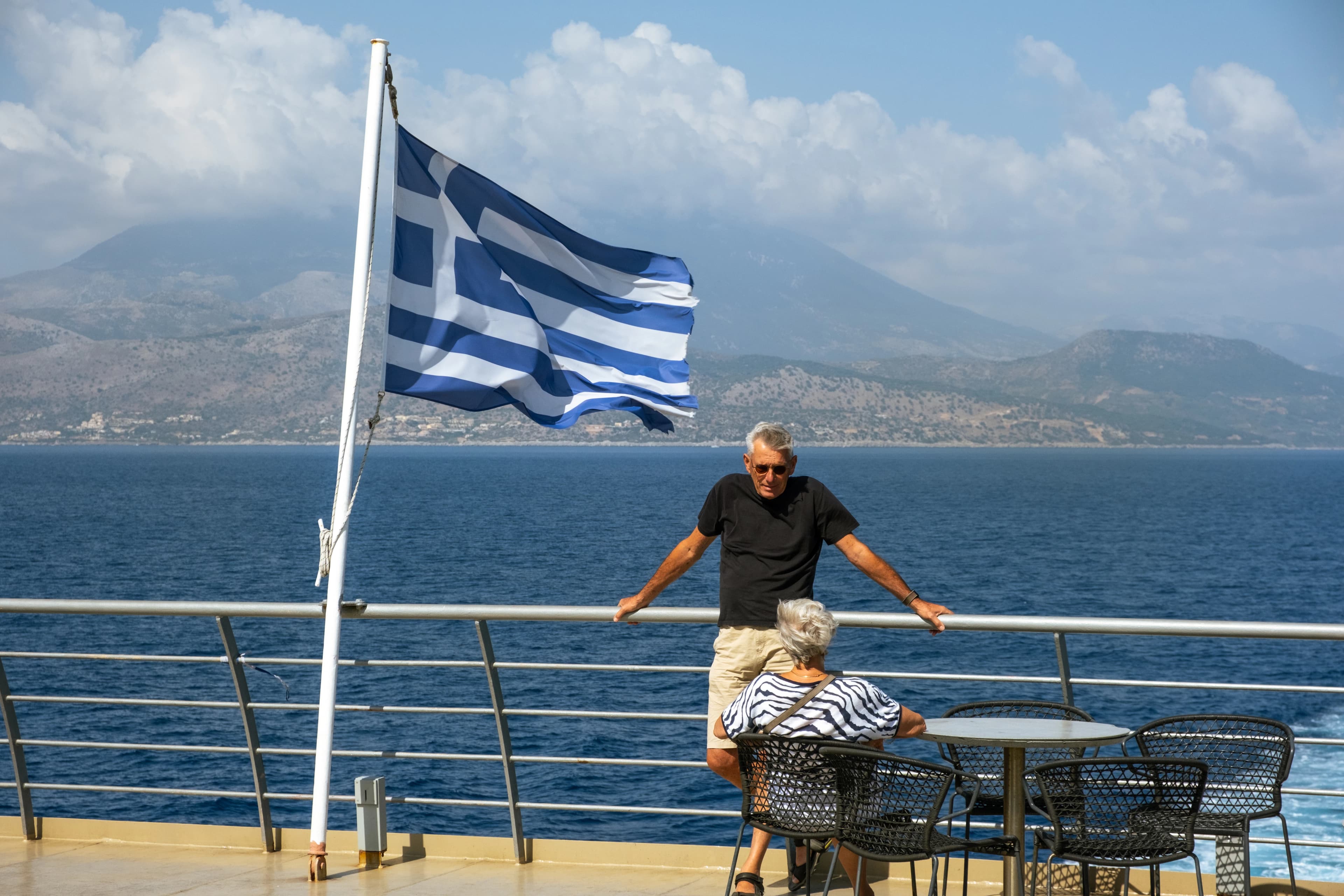 A man standing on a balcony next to a flag