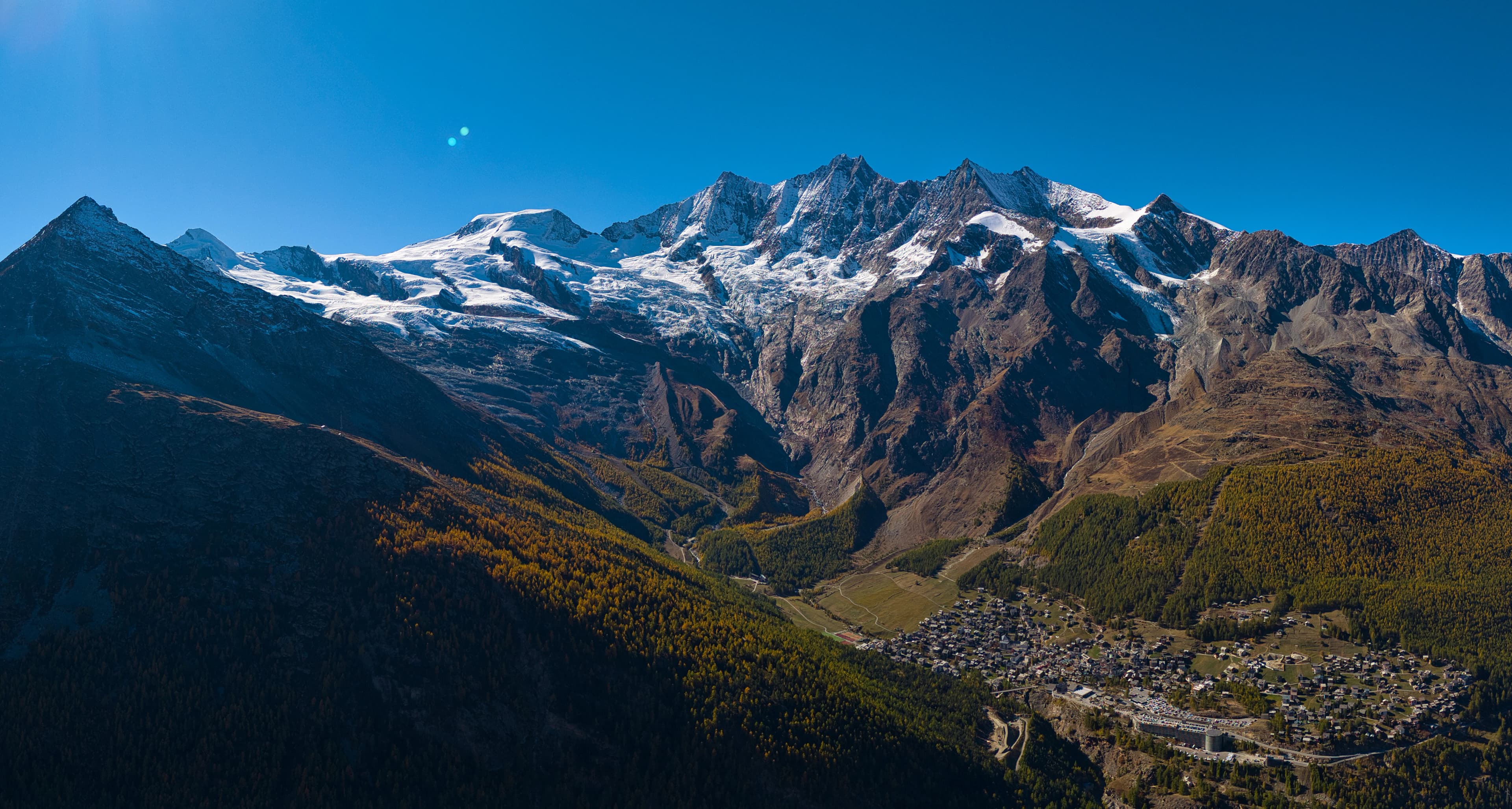 Majestic snow-capped mountains overlook a village below.